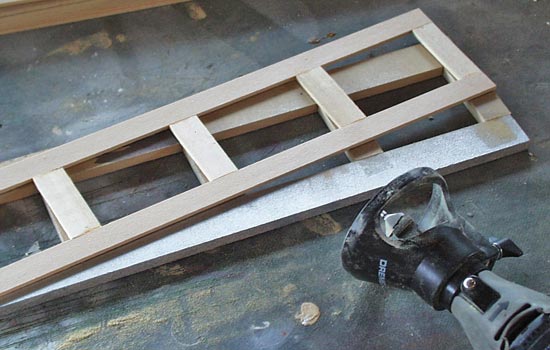  To add the interior router edge I had to build a jig for the router guide (1/4″ MDF) to rest against. I then glued each frame to a sheet of 3/32″ basswood (with the window areas cut out). 