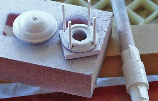 The lamp top and bottom were lathed out of a dowel, with brass rods forming the posts. To make the cage around the outer lens, I masked off the panes with scotch tape and painted with primer.