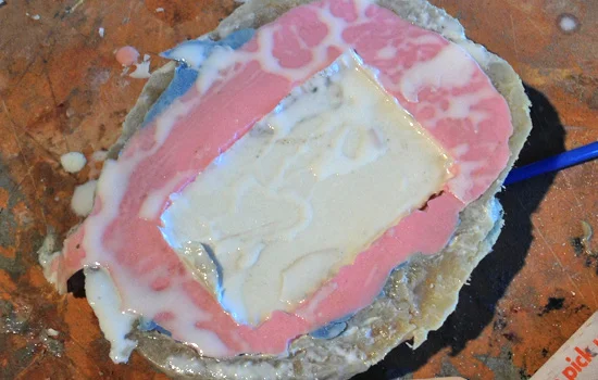 I would mix up a small amount of resin, drop it in the pink mold and then press in the positive white mold, squeezing out any excess.