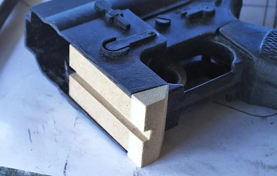 The stock, handle/sight and half of the magazine were hack sawed off the toy to make room for the new parts. A plug of MDF was glued into the magazine well for rigidity and to guide the new magazine.