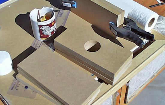  I cut sheets of 3/4″ MDF to laminate into a 9″ x 4″ x 6″ hammer head. I drilled holes through the centers of all sheets. 