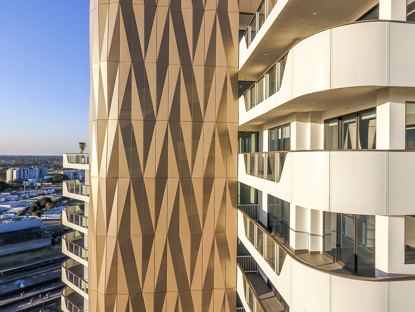 The Crest. Rick Vermey, 2016-19. Folding Light. Geometric origami-folded facade, in powdercoated aluminium, plus timber slatted podium screening. Contemplation of fluid surface patterns led to the artist creating a rhythmically repeating abstract design, which translates both two and three dimensionally into a compelling physical geometry. The result is a considered response to the phenomenon of changing light and shadow.