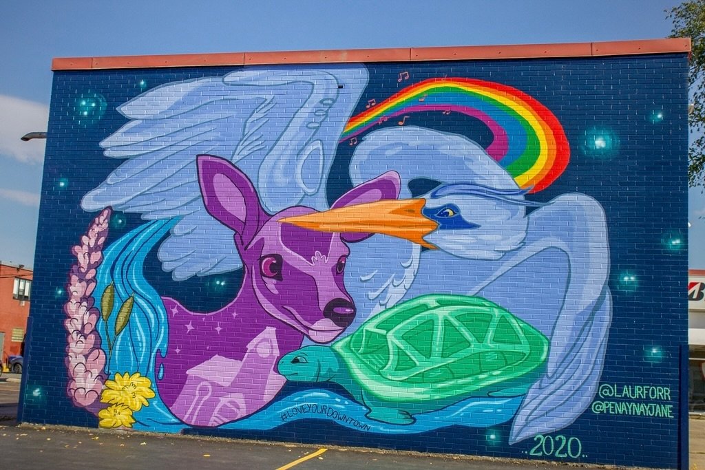 Discover the vibrant symbols in the Community Harmony mural by @laurforr &amp; @penaynayjane in Downtown Fredericton! 🎨 This masterpiece, part of @flourishfestival , celebrates our rich cultural history, environmental diversity, iconic landmarks, an