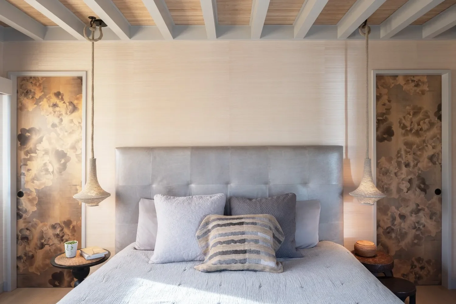 The only non-clay walls are the earthy grasscloth in the primary bedroom and abstract watercolor wallpaper in the hallway bathroom. The grasscloth is accompanied by a pair of crochet pendants, bamboo panels between beams and rare doors clad in exquis