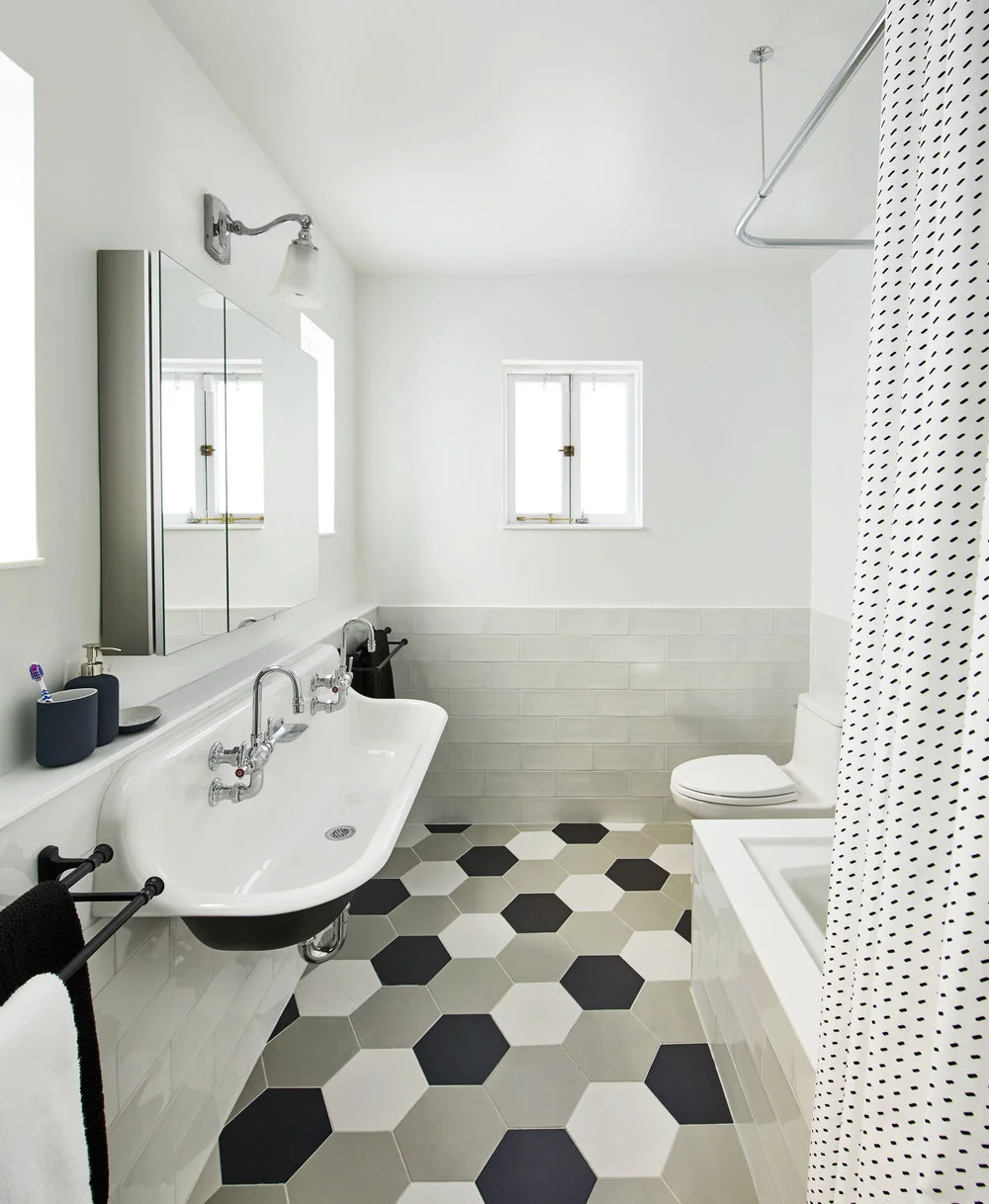 A black and white, double farmhouse sink by Kohler play off of Adko Hexagon tiles for a perfect transitional, modern look in our Carroll Street Cool project.