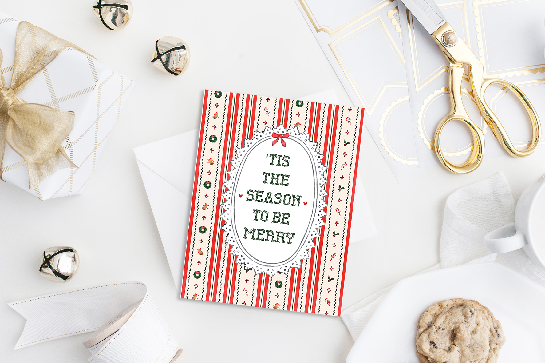 Tis the Season to Be Merry watercolor card featuring candy cane stripes, wreaths, bells, and cross stitch lettering flat lay