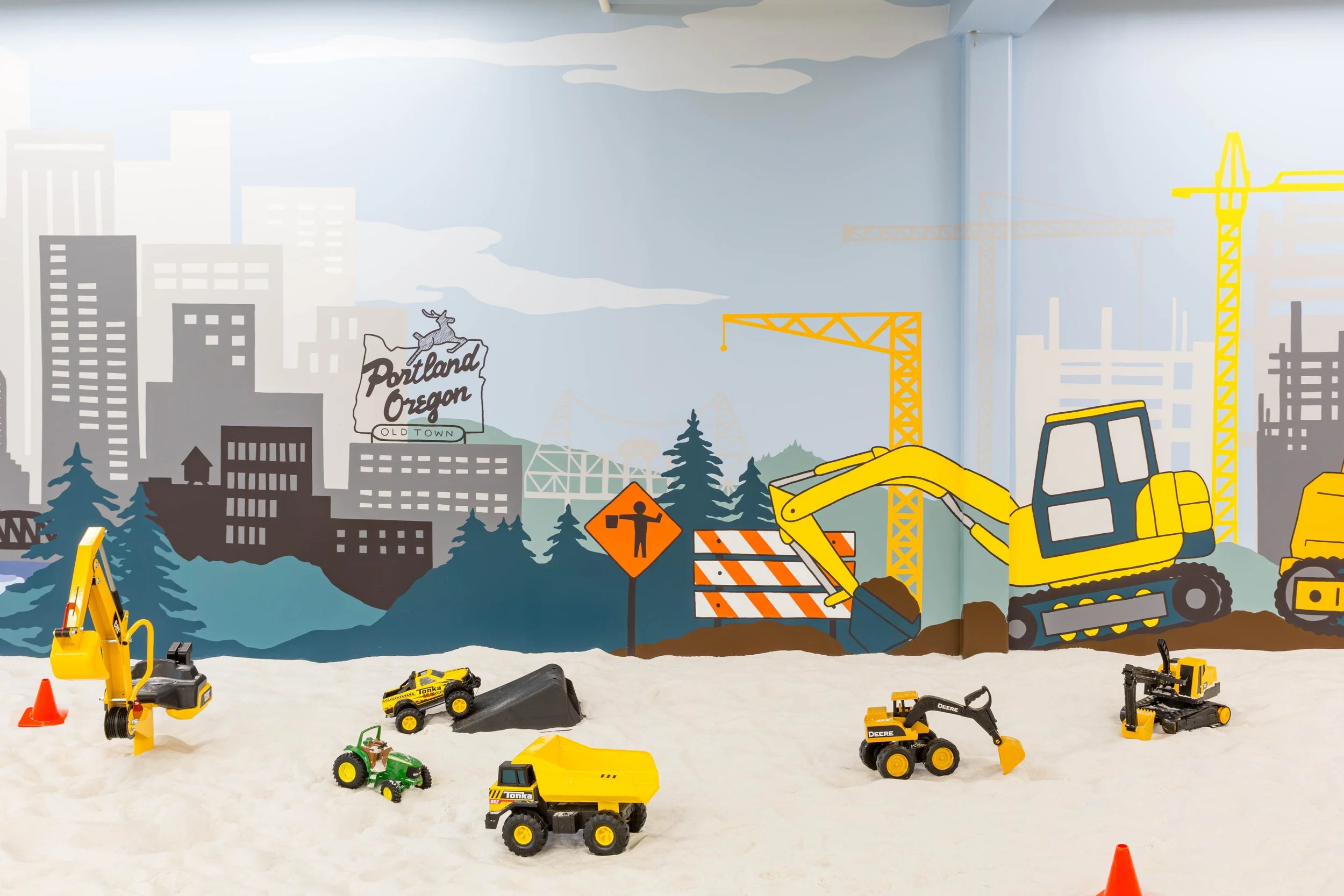 Mural by Oregon artist Amanda Donahue of The Scribblist shows a cityscape of Portland with a construction scene and vehicles