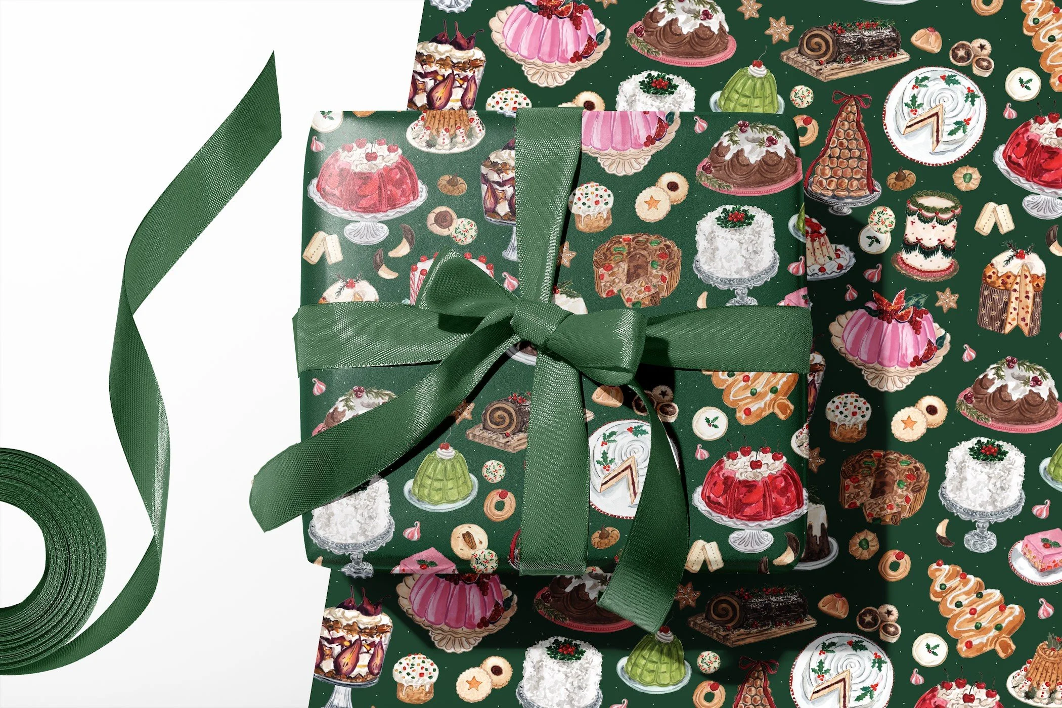 Green Christmas wrapping paper with watercolor vintage holiday desserts, including Yule logs, coconut cakes, gelatin molds, fruitcake and cookies, shown wrapping a gift tied with green satin ribbon