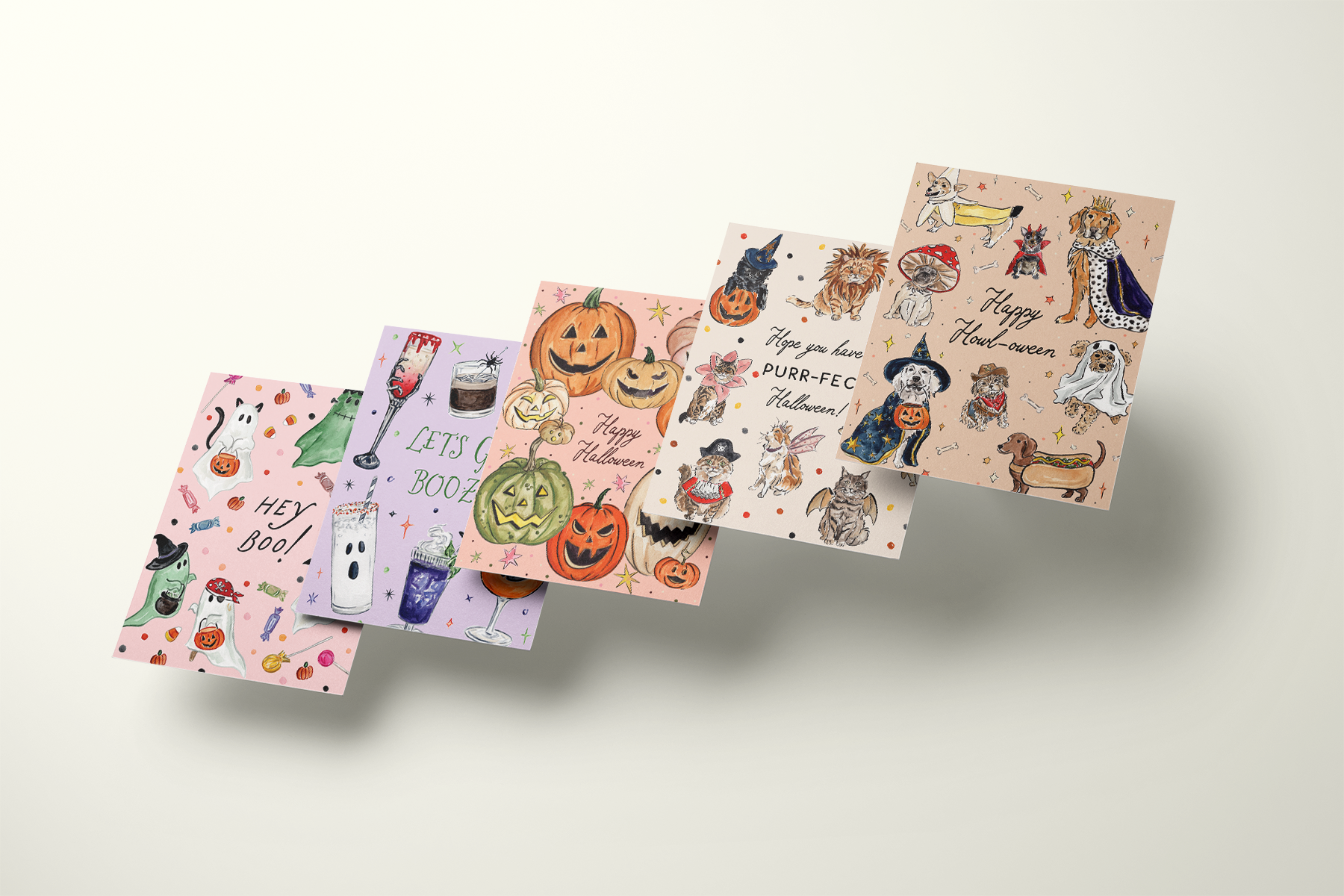 Five watercolor Halloween greeting cards fanned out: Hey Boo ghosts, Let's Get Boo-zy cocktails, jack-o'-lanterns, Purr-fect Halloween cats and Happy Howl-oween dogs