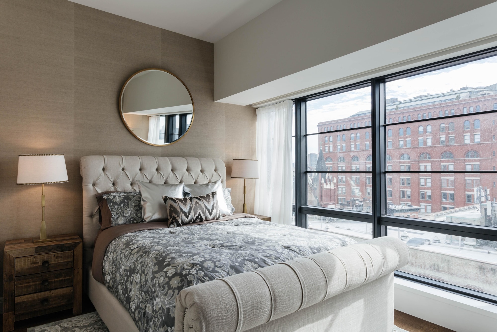 Bedroom with circular mirror hanging above bed
