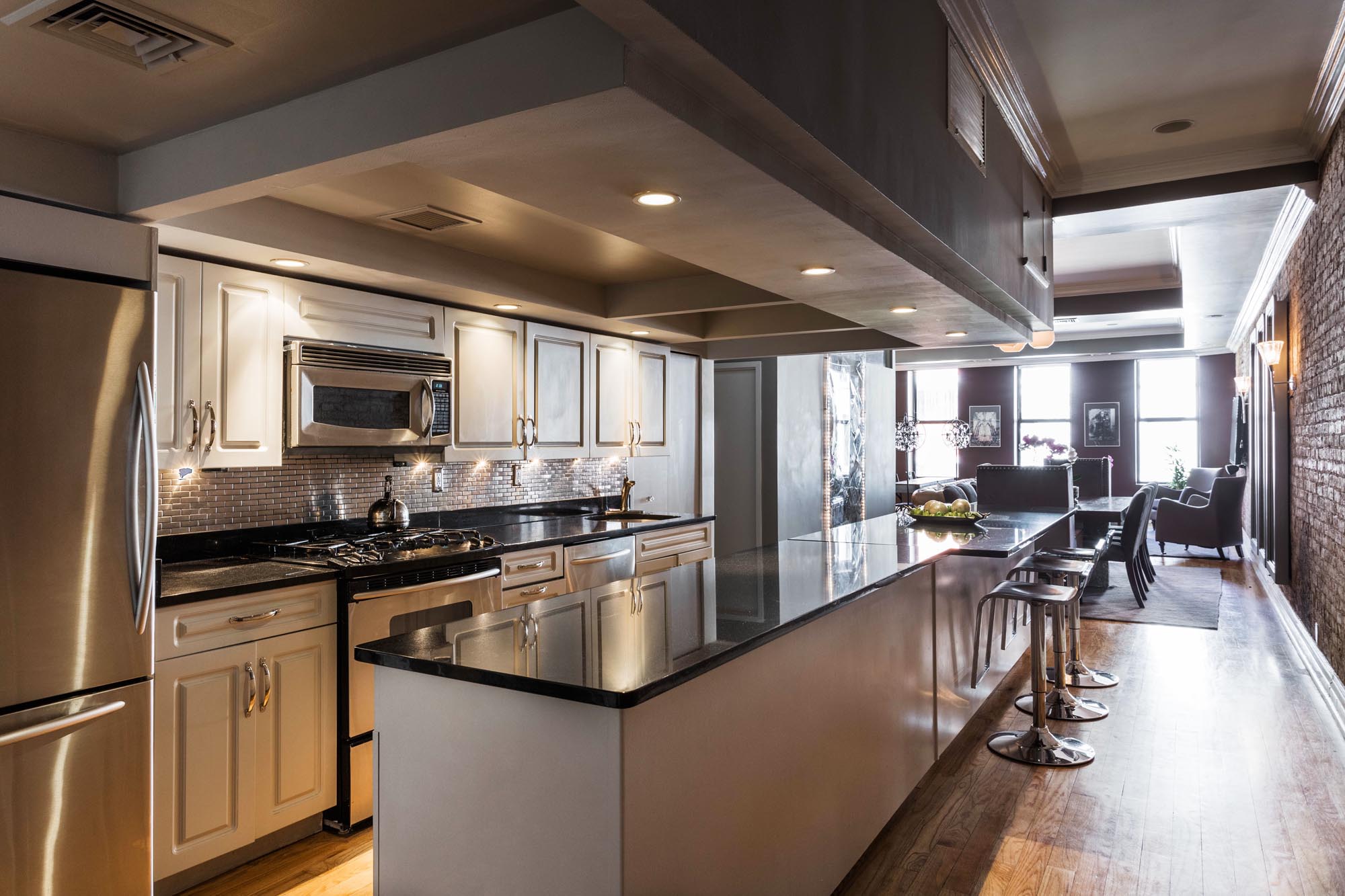 Long kitchen island with black marble counter and high bar stools