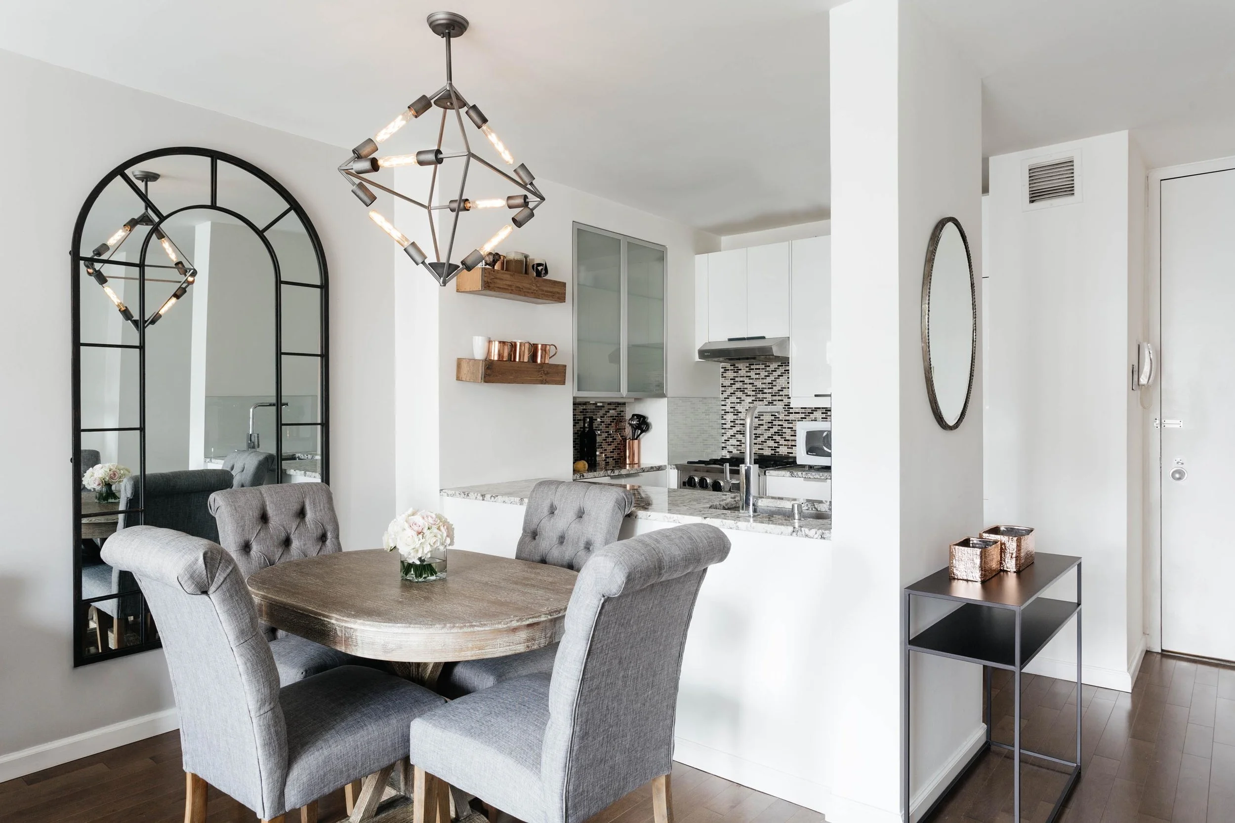 Breakfast nook area with round wooden table and soft grey chairs