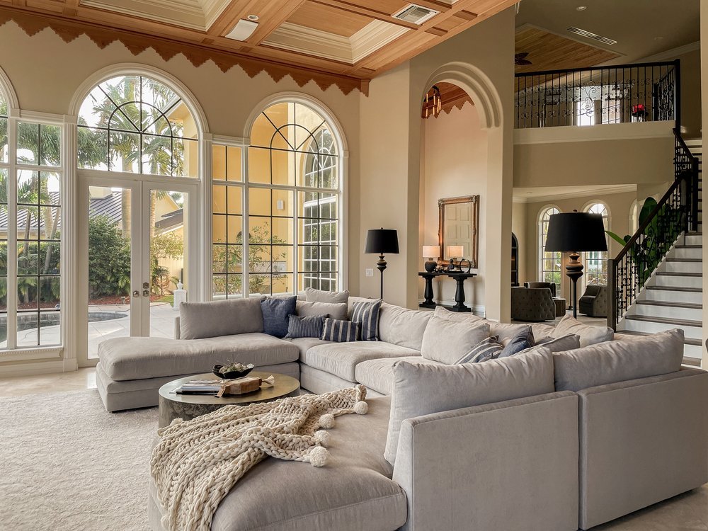 Arhaus couch in living room of a Boca Raton home. Styled with blue striped restoration hardware pillows and contrasting black floor lamps