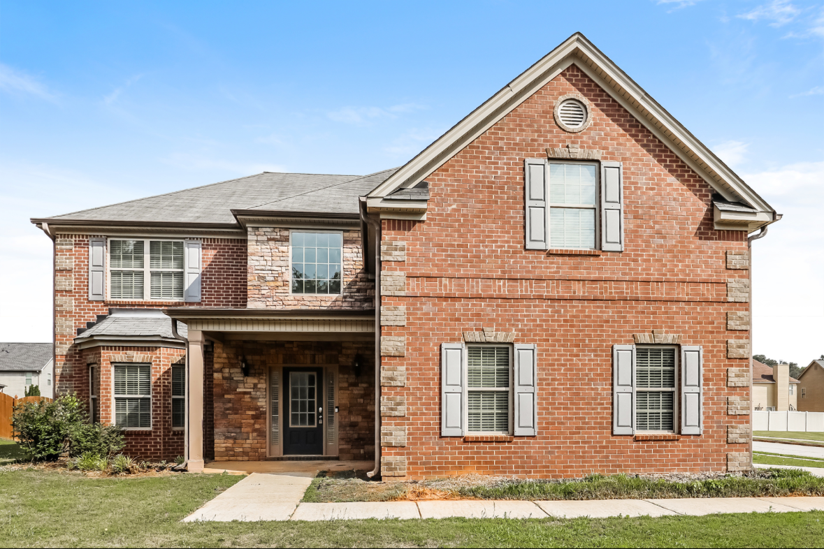 Two-story brick house with gray shutters and a covered front porch.