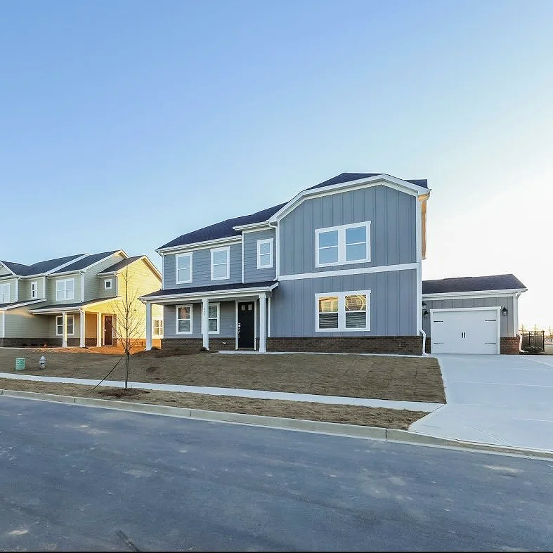 Newly built two-story blue house with white trim and attached garage on a suburban street. StreetScape photographed by, branded by MDM.