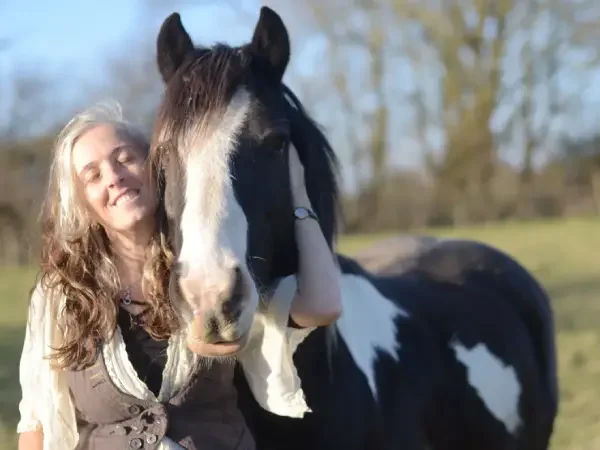 Liz Meadows standing with a horse in a field. Both her and the horse look comfortable and relaxed.