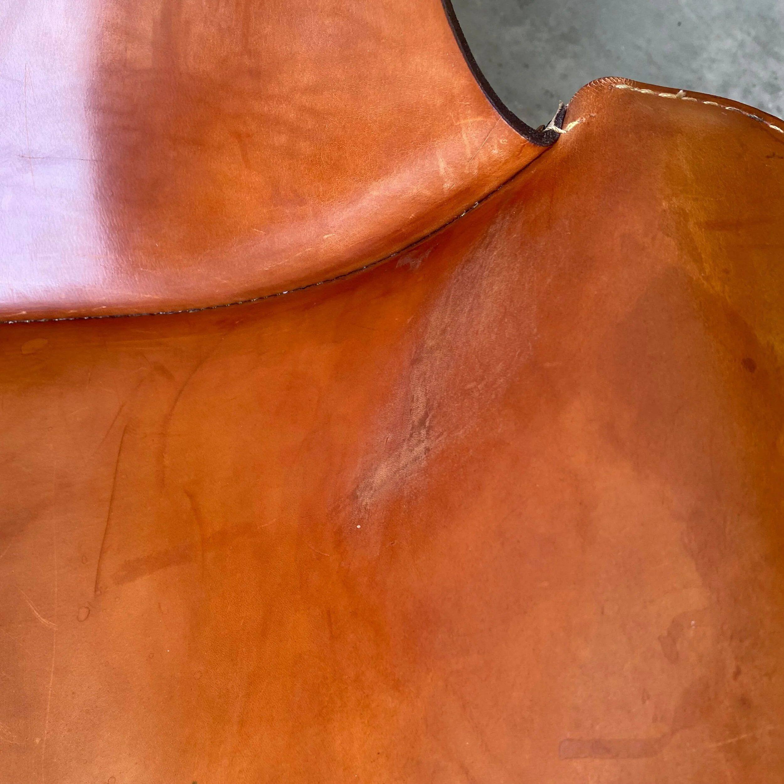 A striking pair of all original leather and iron sling chairs with swivel bases.   These show age appropriate wear but look beautiful overall.   Very fine examples, sold as a pair.  