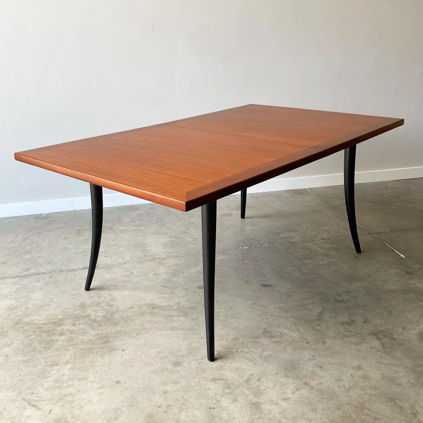 A stunning mahogany dining table with black lacquered saber leg base.  A mid century modern classic from Harvey Probber.   Newly refinished with minor imperfections from age and use