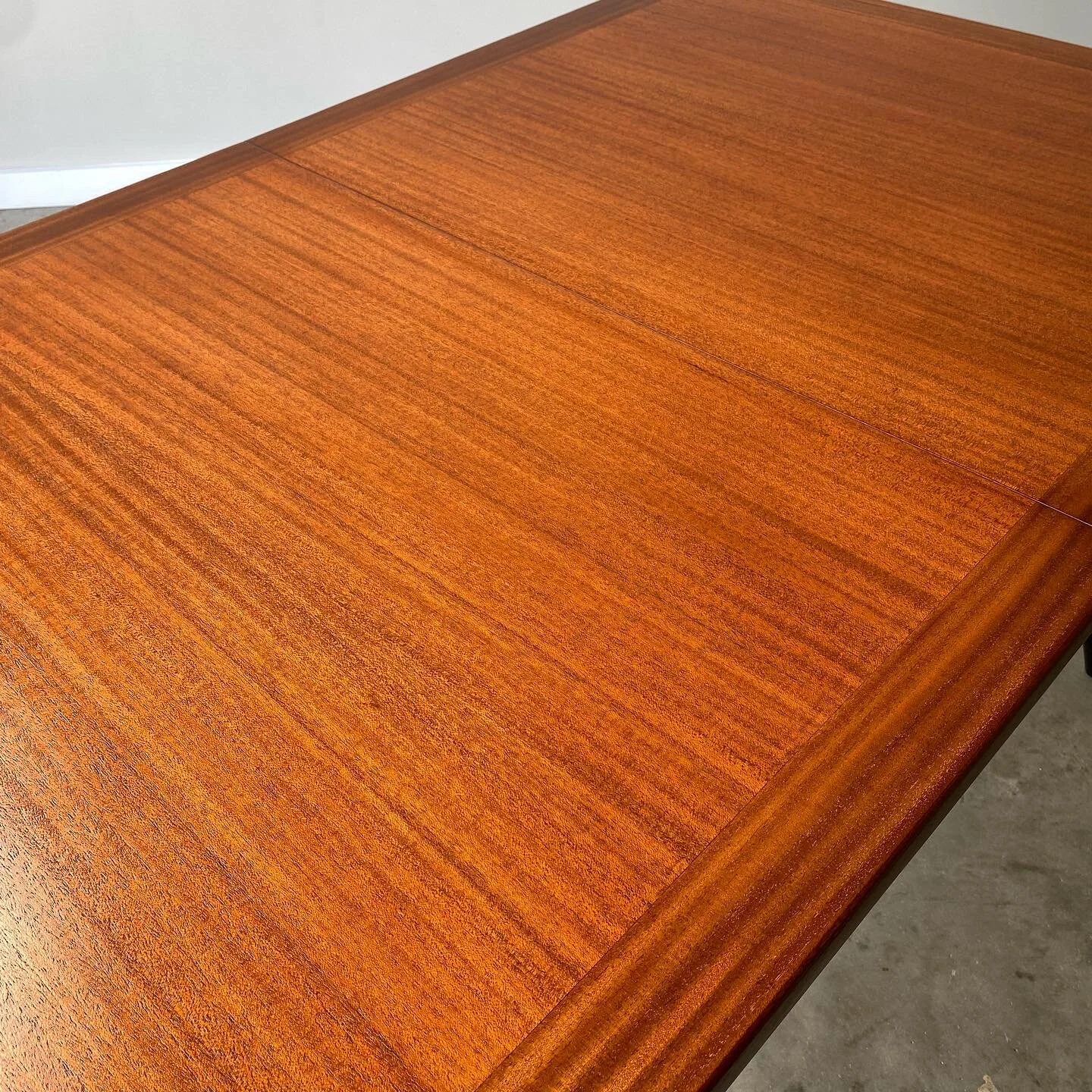 A stunning mahogany dining table with black lacquered saber leg base.  A mid century modern classic from Harvey Probber.   Newly refinished with minor imperfections from age and use