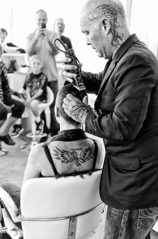 Tod Alan of Azure Hair Studio applies the finishing touches to Trina Klier-Murri’s hair shaving as friends and family look on. 