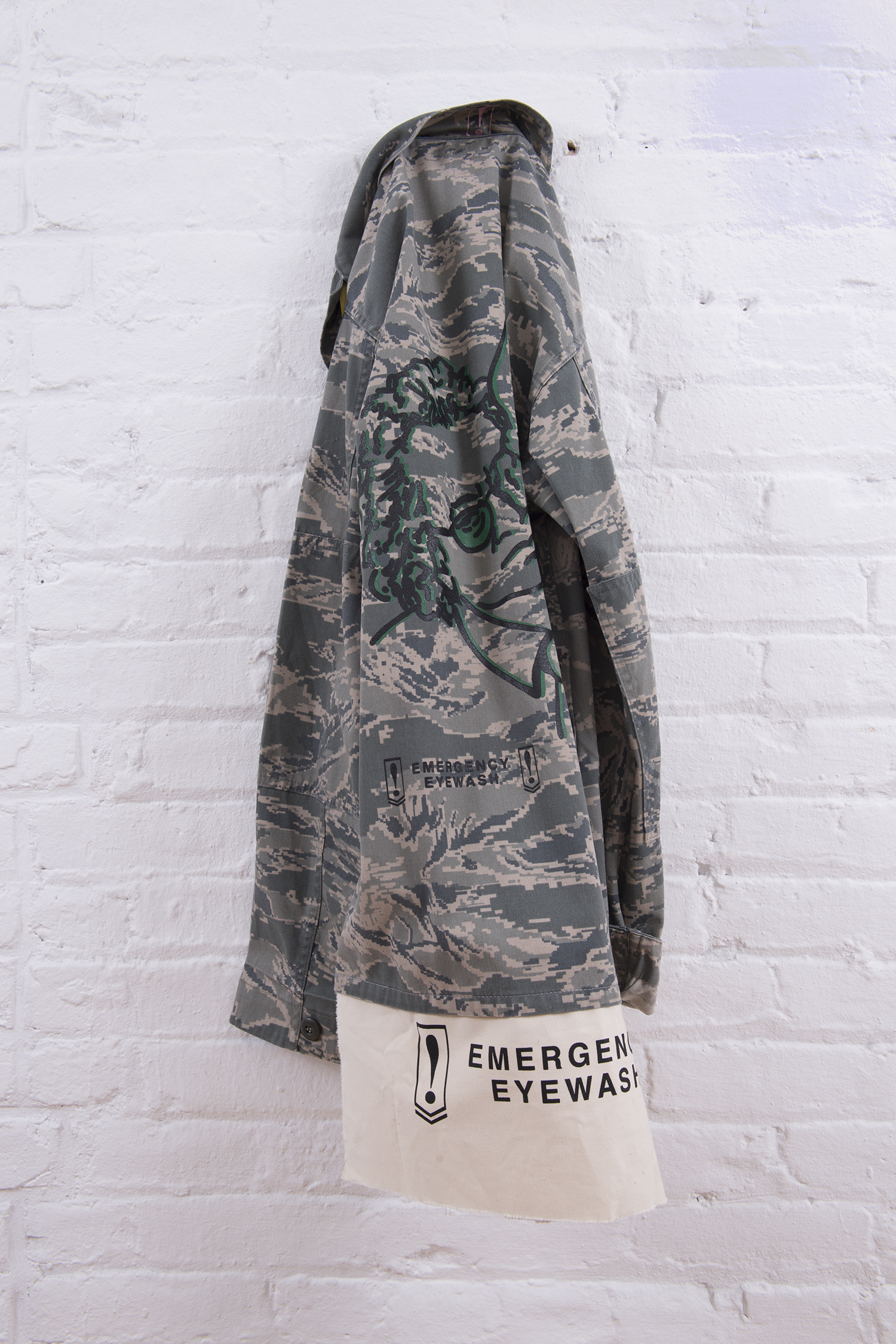 Ahem. Carol Szymanski & Xiaofu Wang. 2018. Vintage military camouflage jacket with Emergency Eyewash patches and silkscreen images