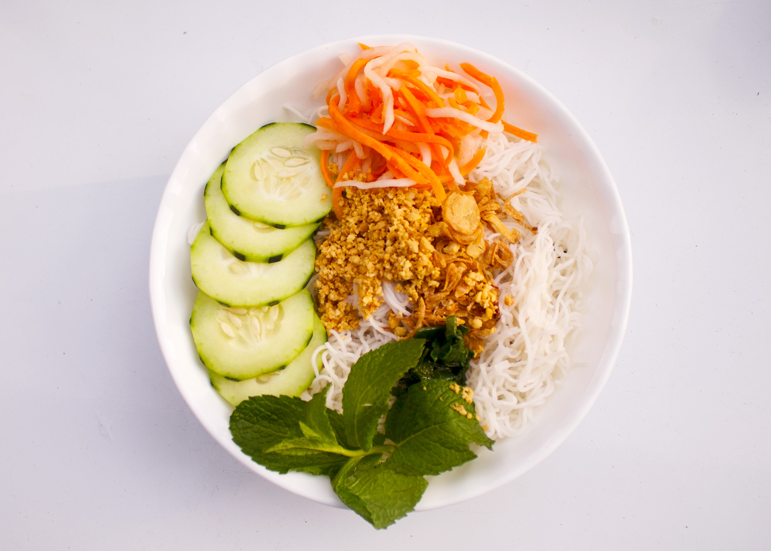 Rice vermicelli salad topped with variety of green and peanuts