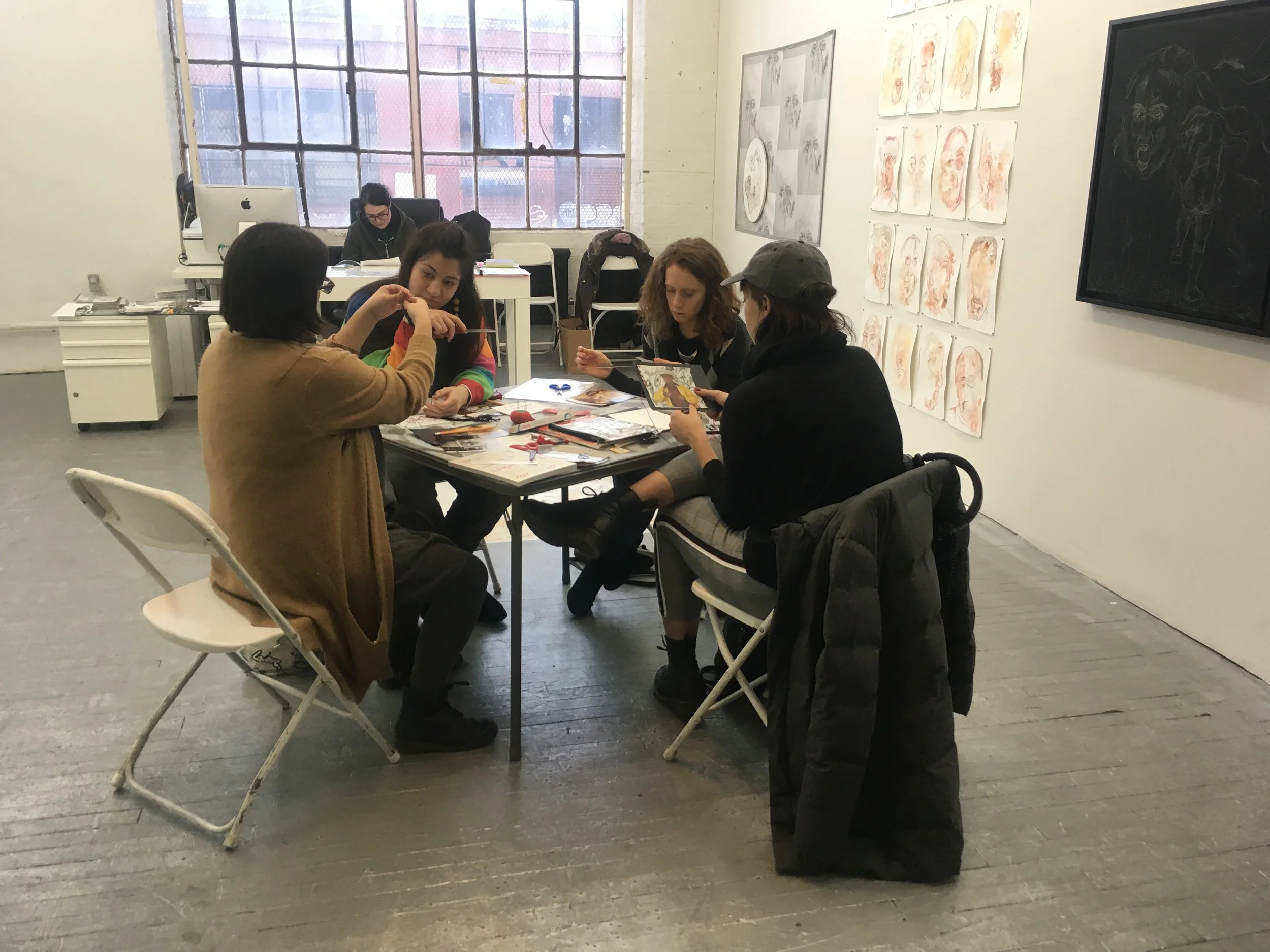 Embroidering on found images at Amos Eno Gallery