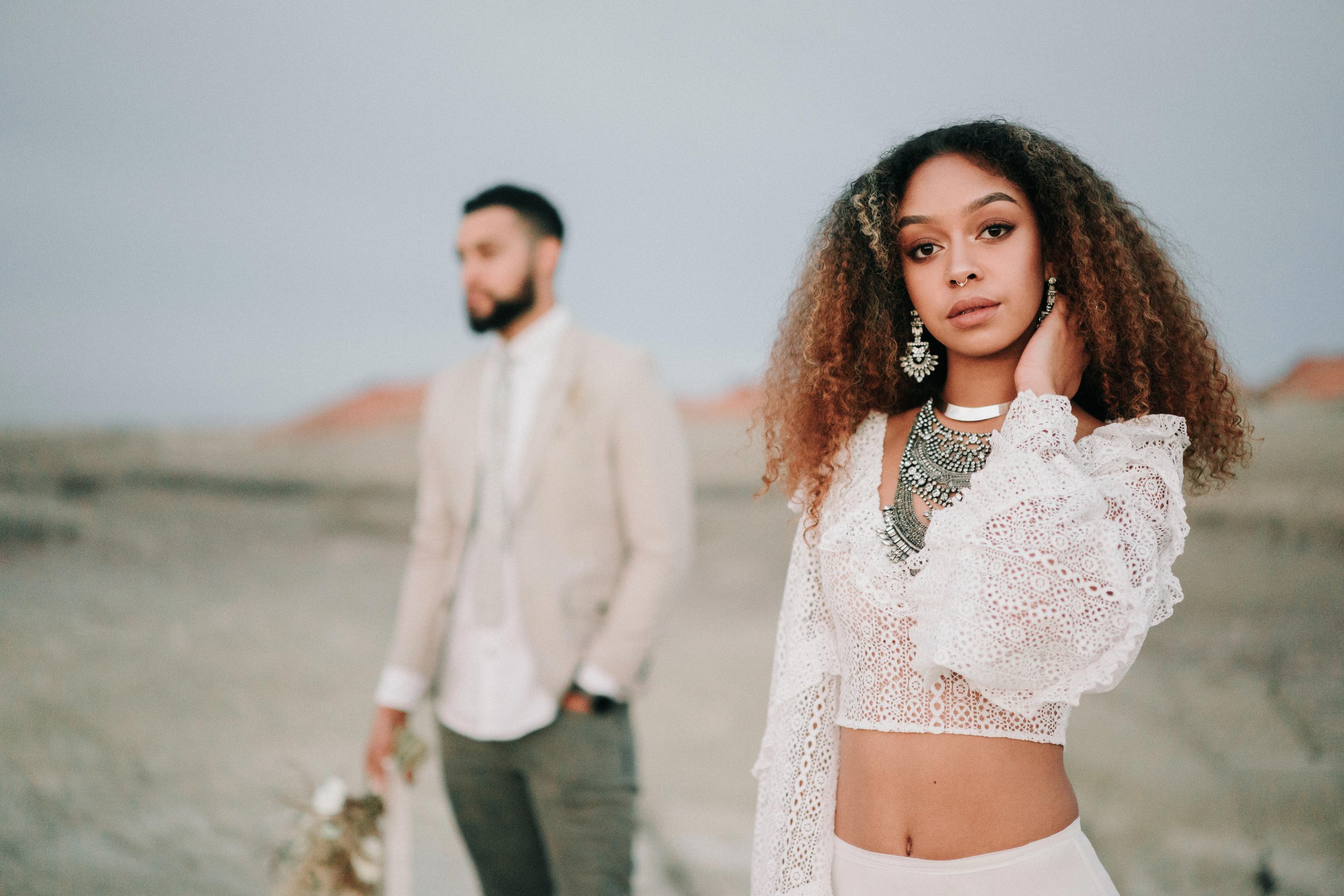 Stylish bride and groom posing together on a sandy desert landscape under soft pastel skies, photographed by Bend, Oregon wedding photographer Tony Gambino.