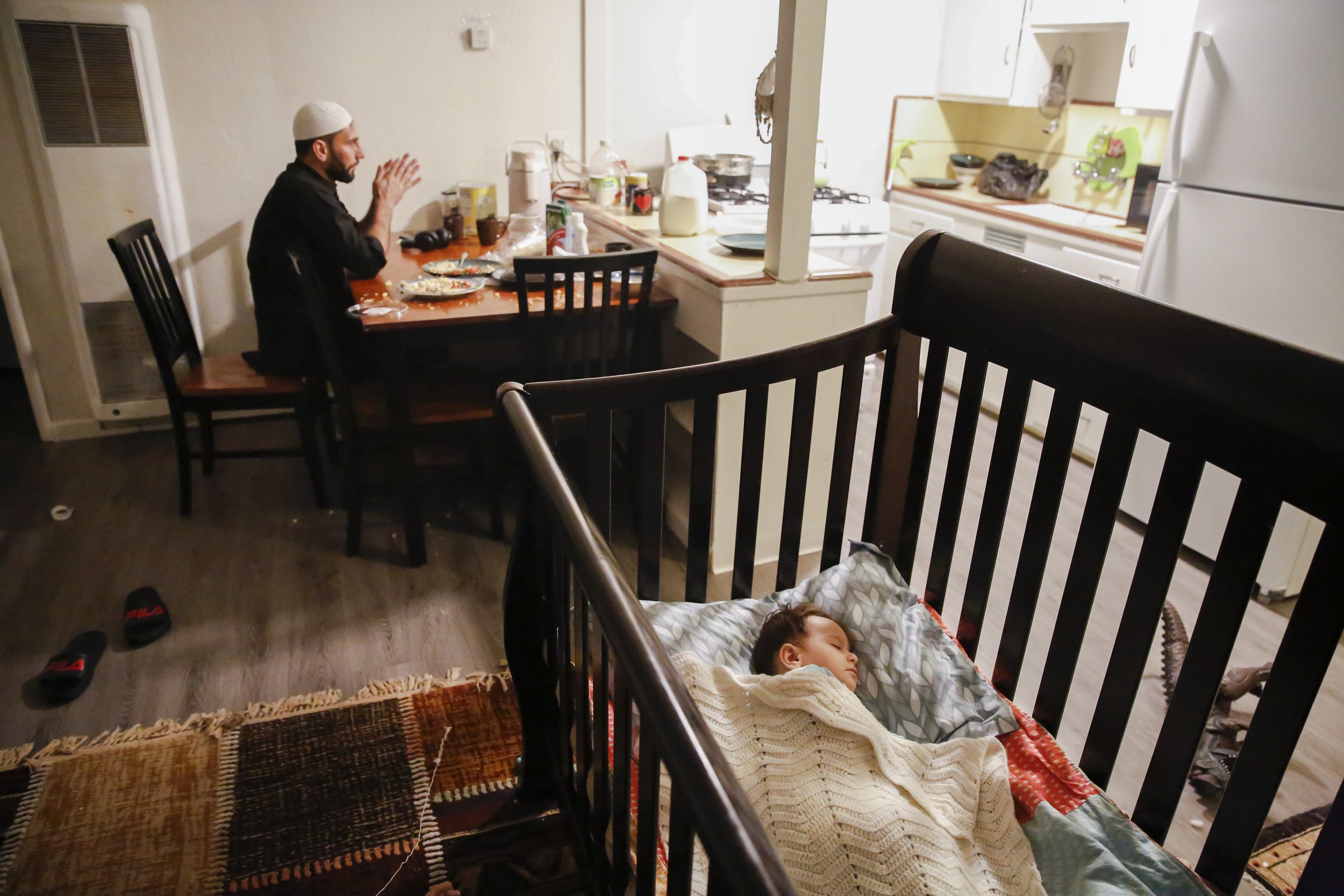  Najibullah Mohammadi sits at the dining table while his son Yasar Mohammadi (2), sleeps in his crib a few feet away in the living room of their one bedroom apartment in Sacramento, Calif. on Sunday, March 27, 2022. Najibullah Mohammadi, his wife Sus