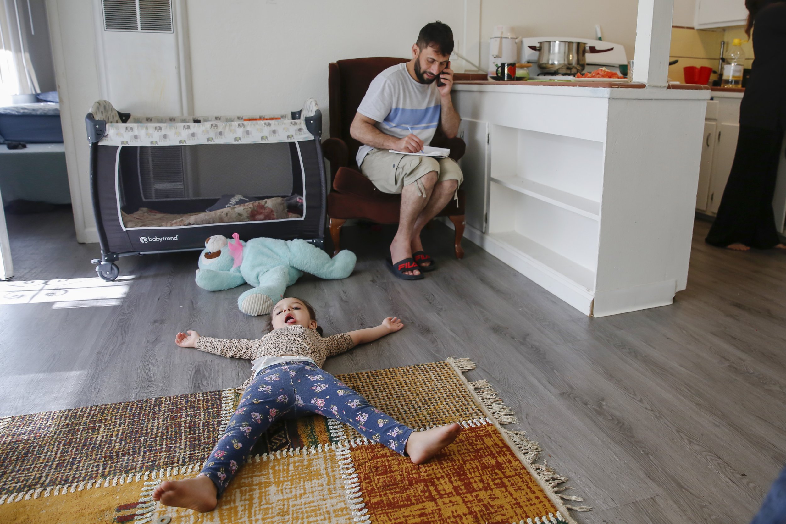  Najibullah Mohammadi talks with a friend on the phone who is helping him register for classes at the local community college, while his daughter Zahra lays on the floor and his wife Susan cooks lunch at their home in Sacramento, Calif. on Tuesday, M