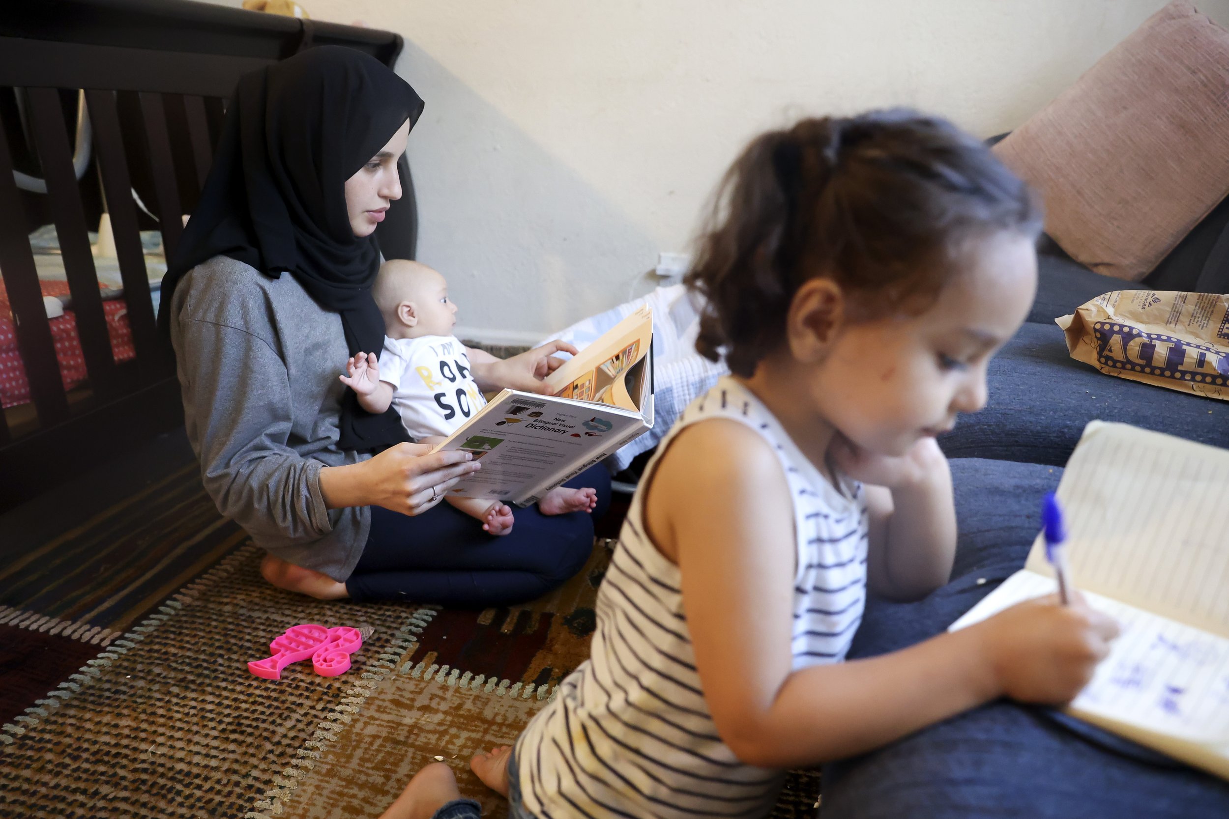  Susan Mohammadi looks over a Dari to English picture book in order to practice her english while she takes care of her two-month-old son Yusuf and three-year-old daughter Zahra at their home in Sacramento, Calif. on Tuesday, July 12, 2022. Najibulla