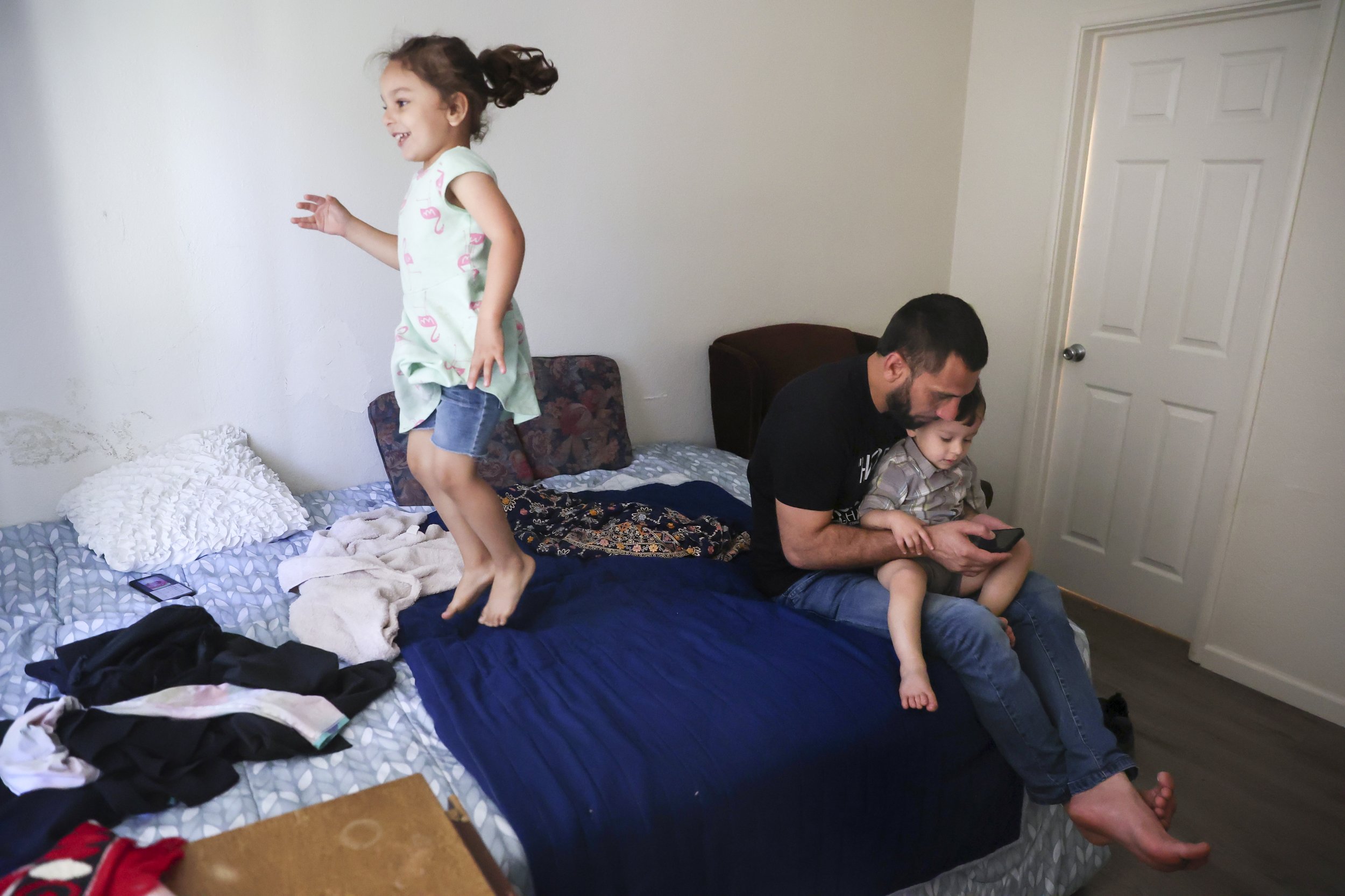  Zahra Mohammadi jumps on her parents bed while Najibullah Mohammadi watches videos with his son at their home in Sacramento, Calif. on Tuesday, May 31, 2022. Najibullah Mohammadi, his wife Susan, their two young children Zahra and Yasar, and their s