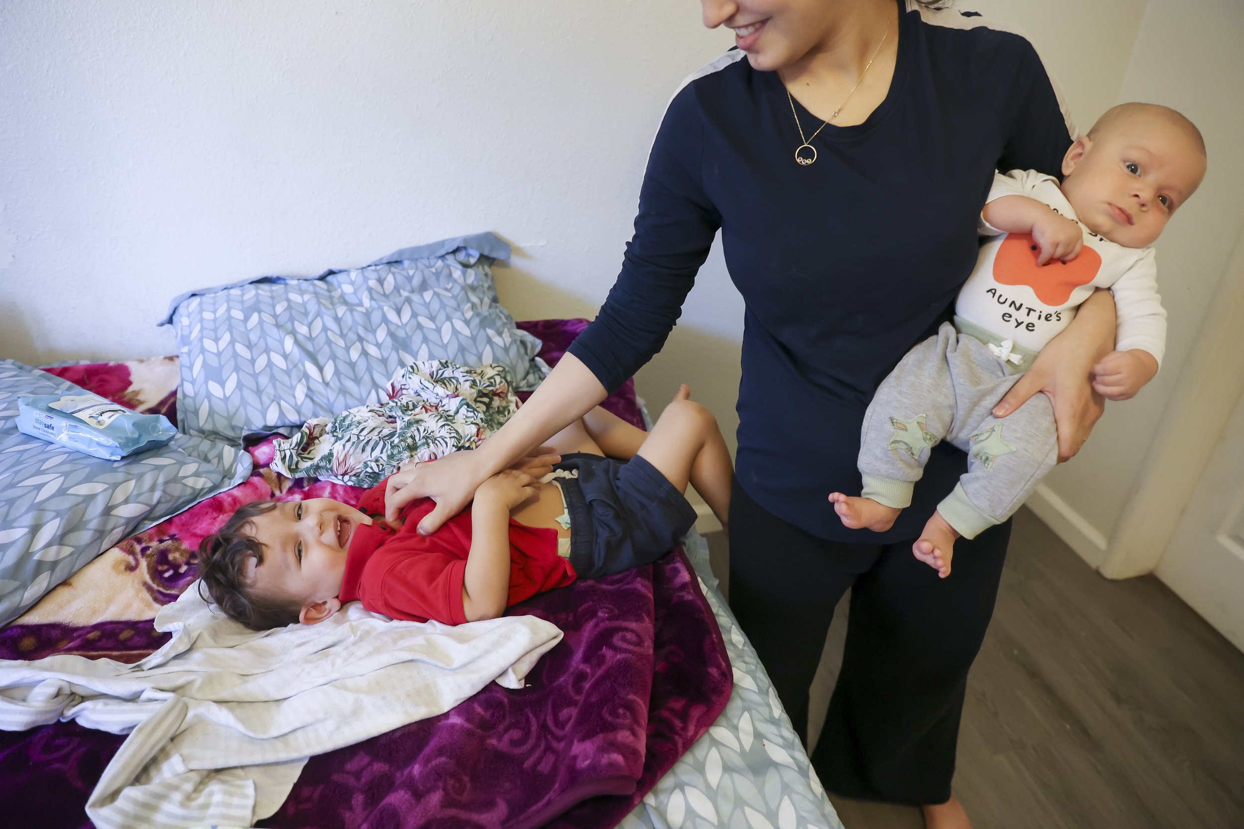 Susan Mohammadi holds her two-month-old son Yusuf Mohammadi while she plays with her older son Yasar (1) on her bed at home in Sacramento, Calif. on Thursday, July 21, 2022. Najibullah Mohammadi, his wife Susan, their two young children Zahra and Ya