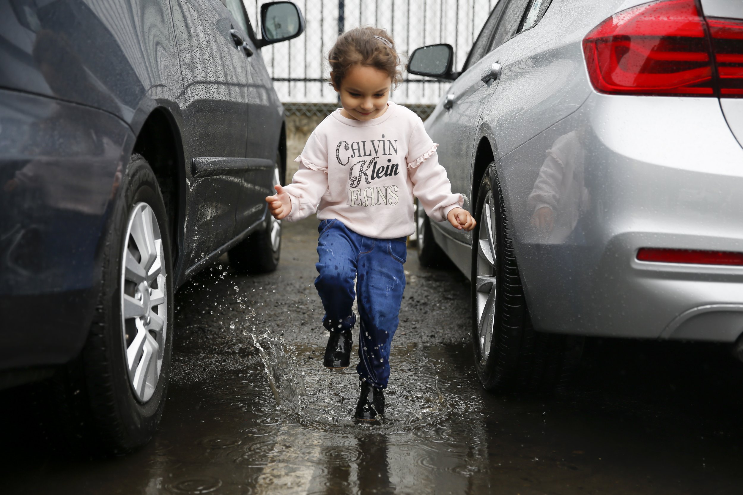  Zahra Mohammadi jumps in rain puddles after she get’s out of her parent’s car outside their home in Sacramento, Calif.  on Thursday, April 14, 2022. Najibullah Mohammadi, his wife Susan, their two young children Zahra and Yasar, and their soon-to-be