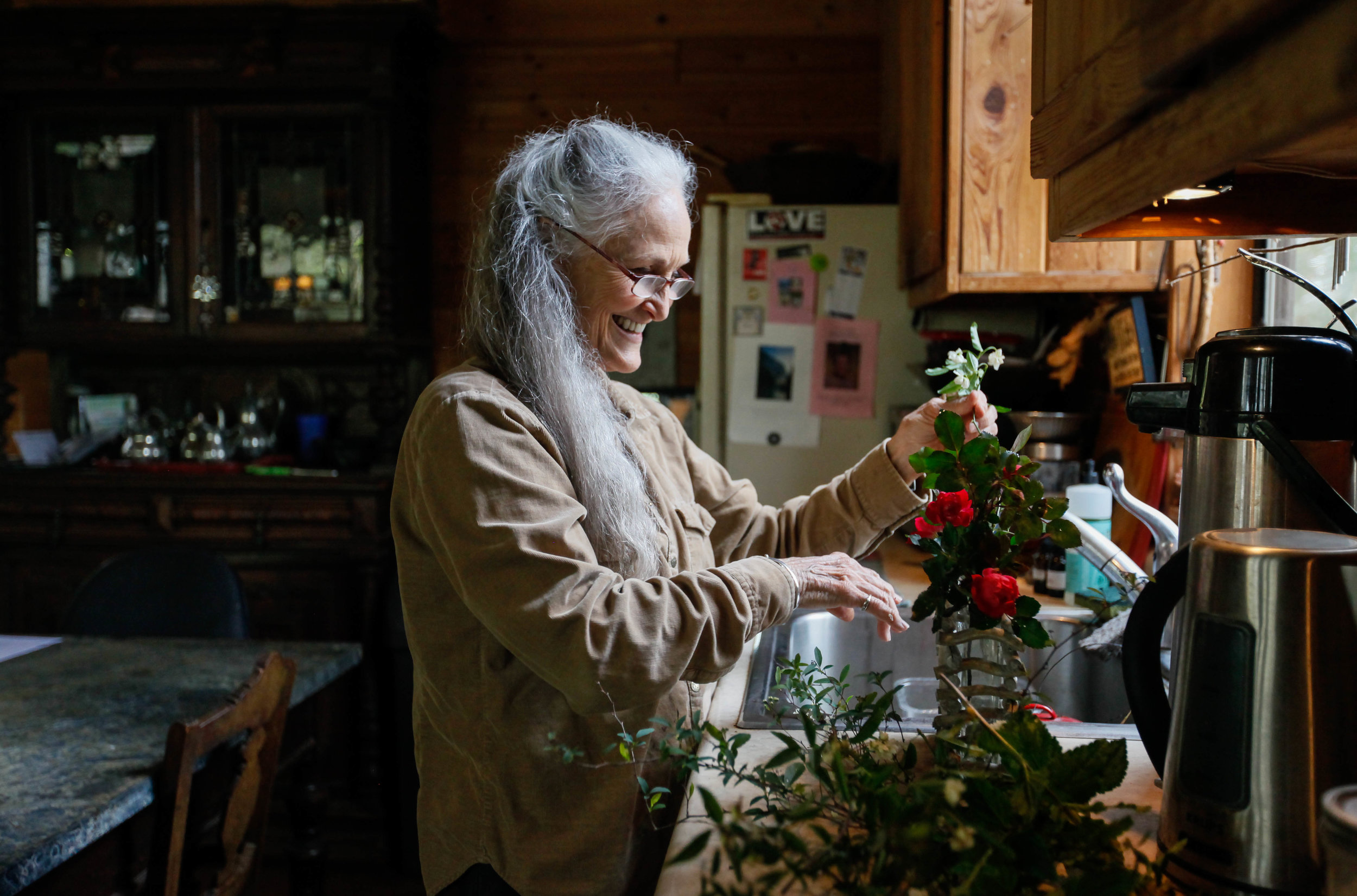 Tina Tinsley, 75, a psychotherapist and founder of Earthsong, places some freshly picked roses in a vase at her home in Earthsong on Saturday, April 7, 2018. 