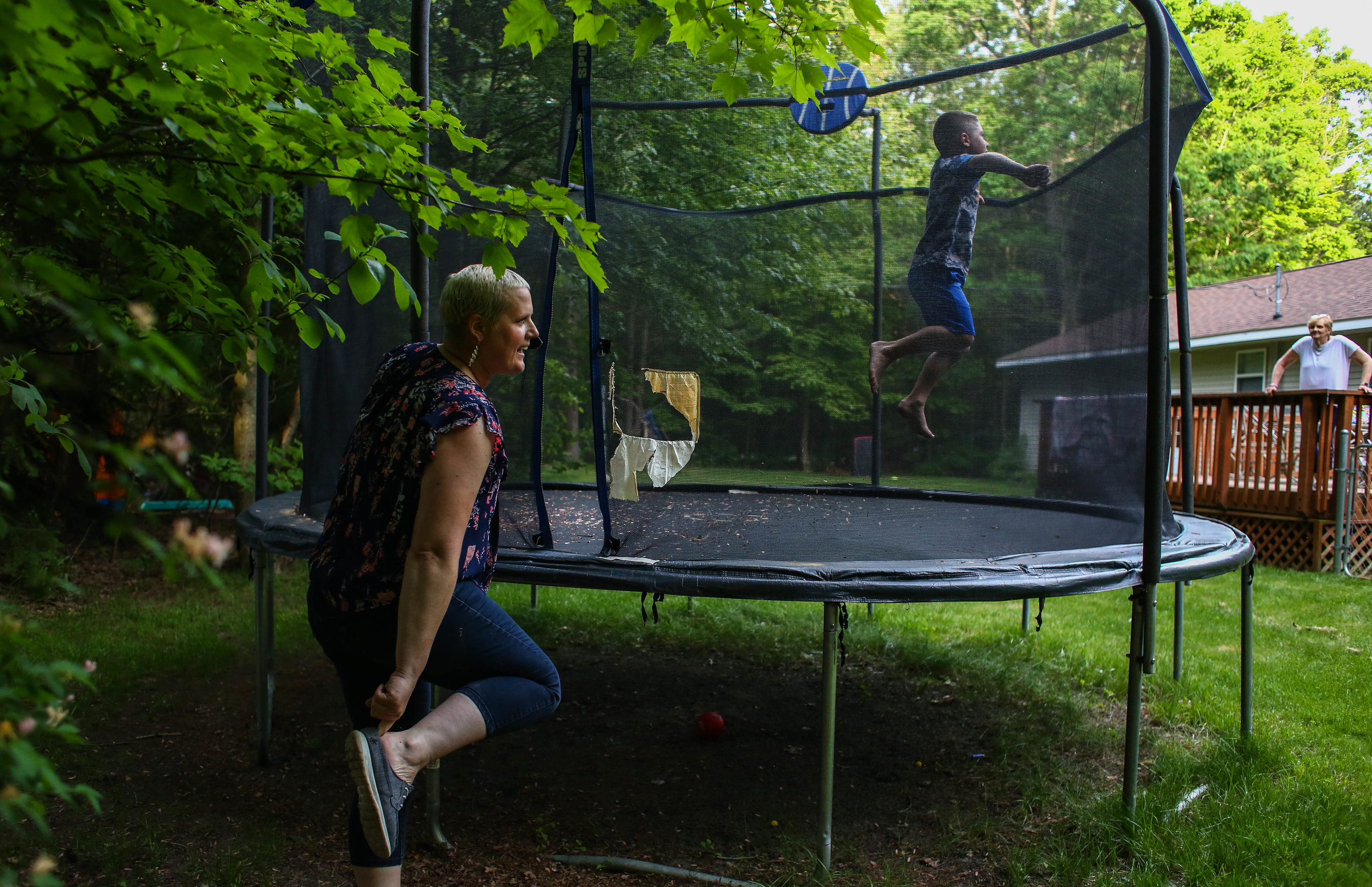  Amanda Cihak puts back on her shoes after jumping on the trampoline with her son Cameron while her mother Janet watches from the back porch at their house, in Muskegon, Michigan on Saturday, June 8, 2019. 