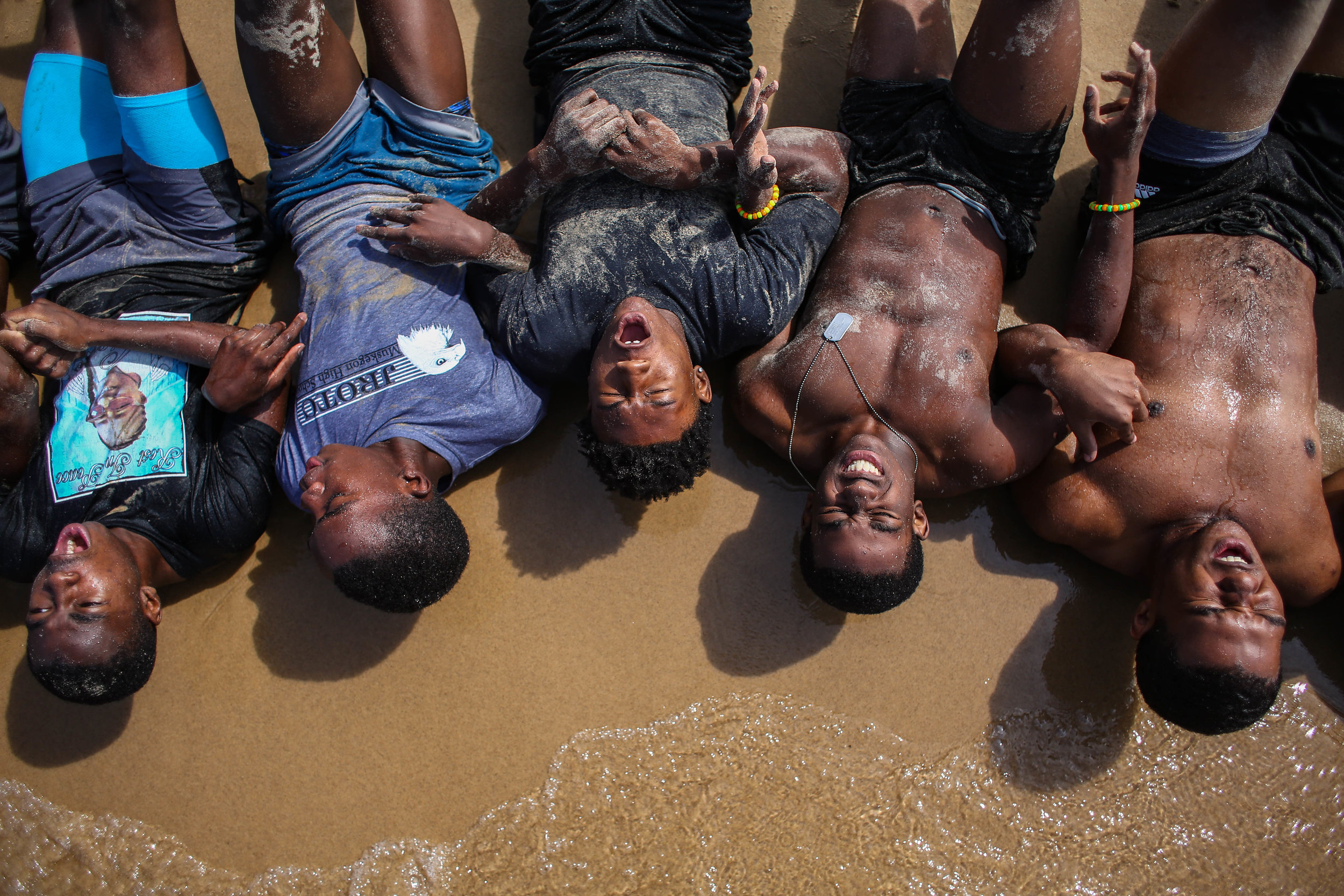  Muskegon and Saginaw Swan Valley High School football players do sit-ups while linked together during their grueling Marine-style beach and water workout at Pere Marquette Beach in Muskegon on Friday, July 26, 2019. 