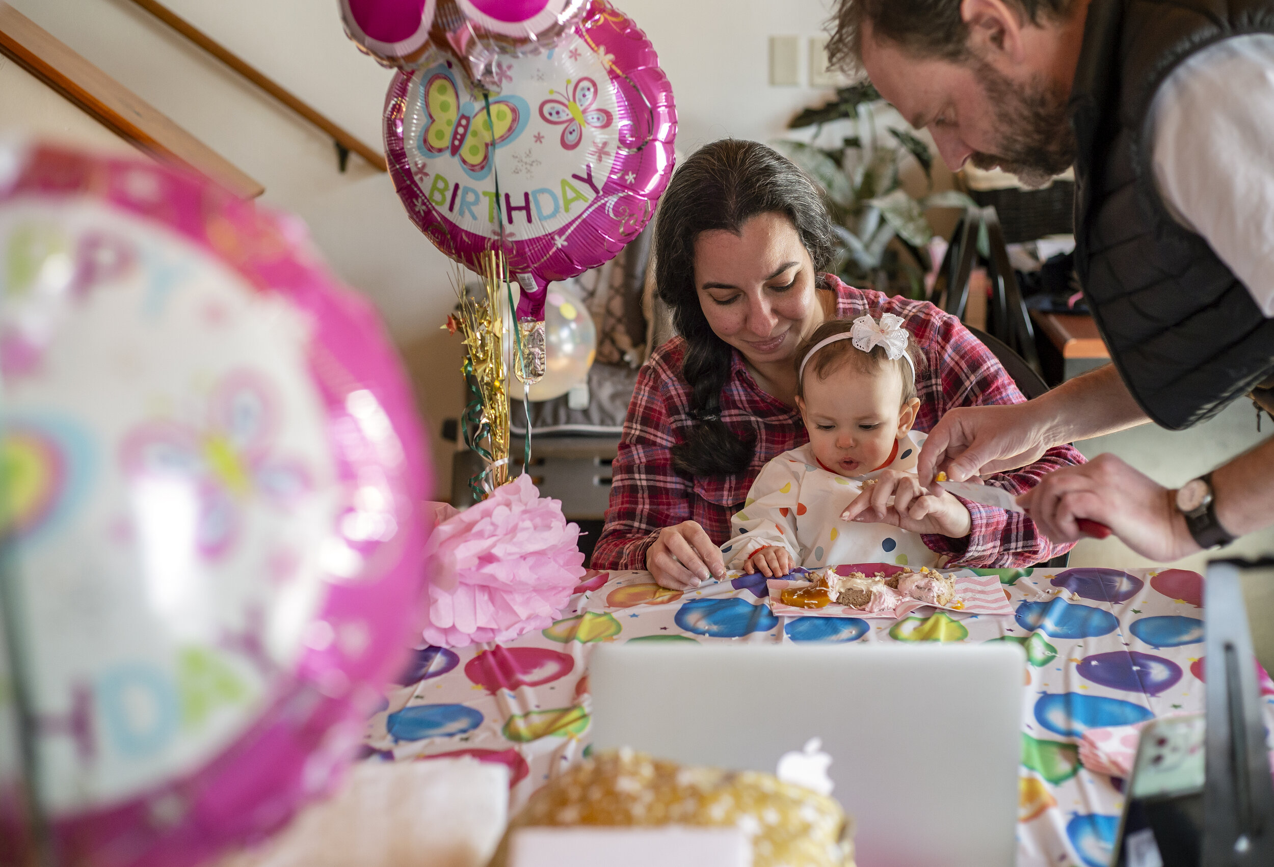  Metcalf and Souza help Isadora eat a piece of birthday cake that Souza made while friends and family celebrate her first birthday via Zoom call on March 6, 2021.  