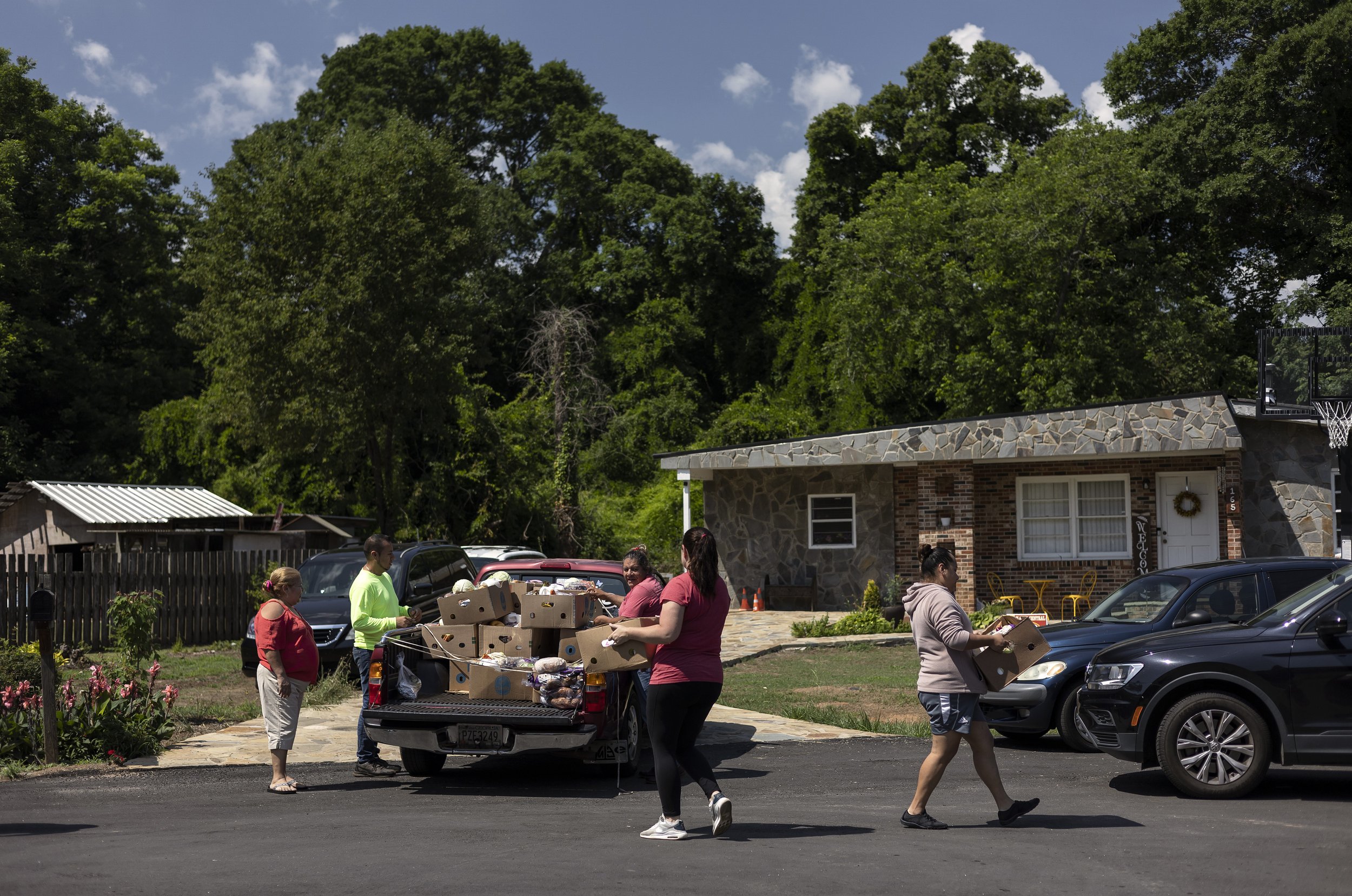  Angel Torres, husband to Esther Carrillo, helps distribute food outside his family’s home on Thursday, June 2, 2022 in Athens. Through their efforts, they help feed more than 30 families on a weekly basis. Many immigrants and people part of the Lati