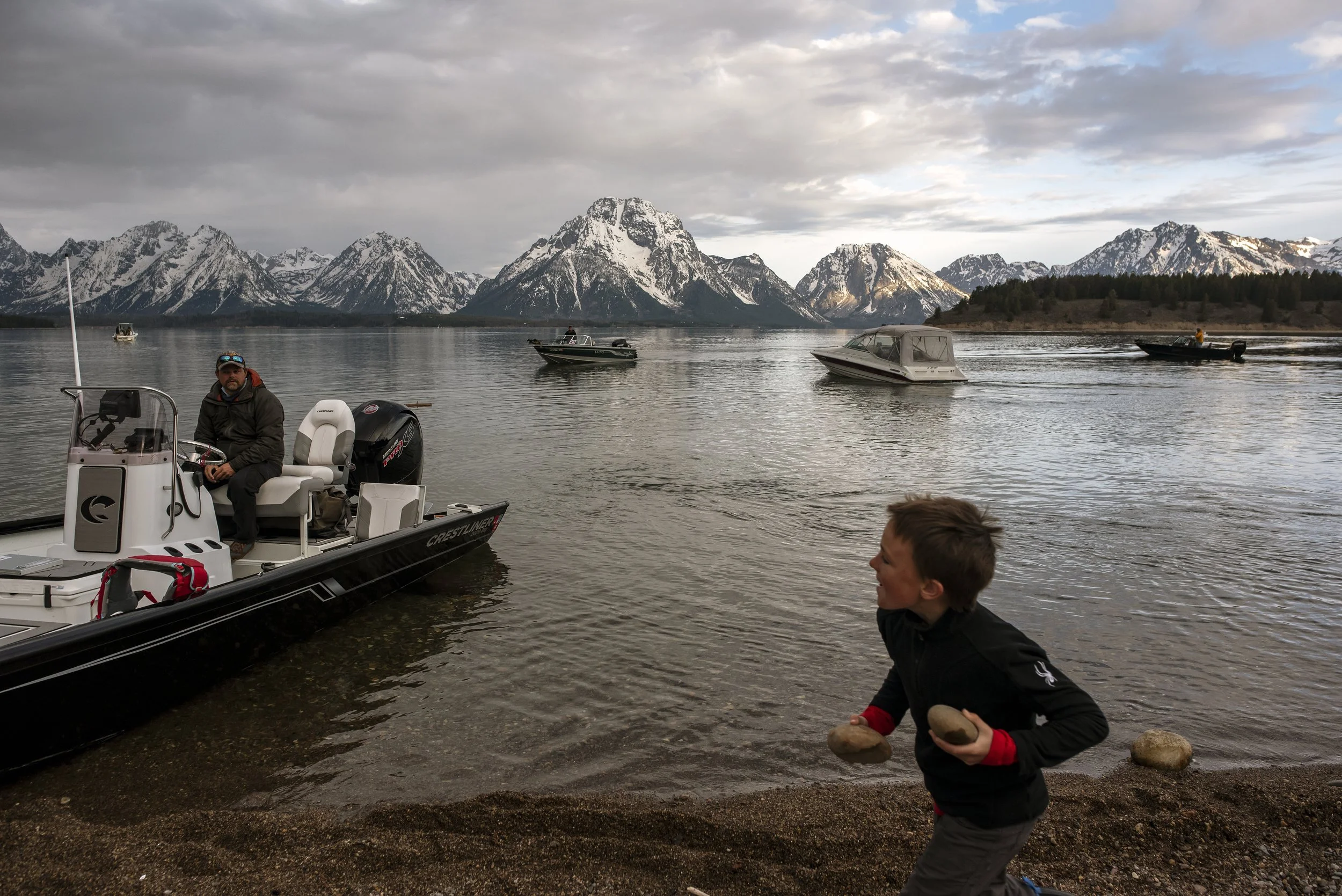  Cecil Dornan, 8, entertains himself by collecting rocks while teams launch into Jackson Lake as the sun rises over the Tetons during Saturday’s Ice Off Fishing Derby on May 19, 2021. 