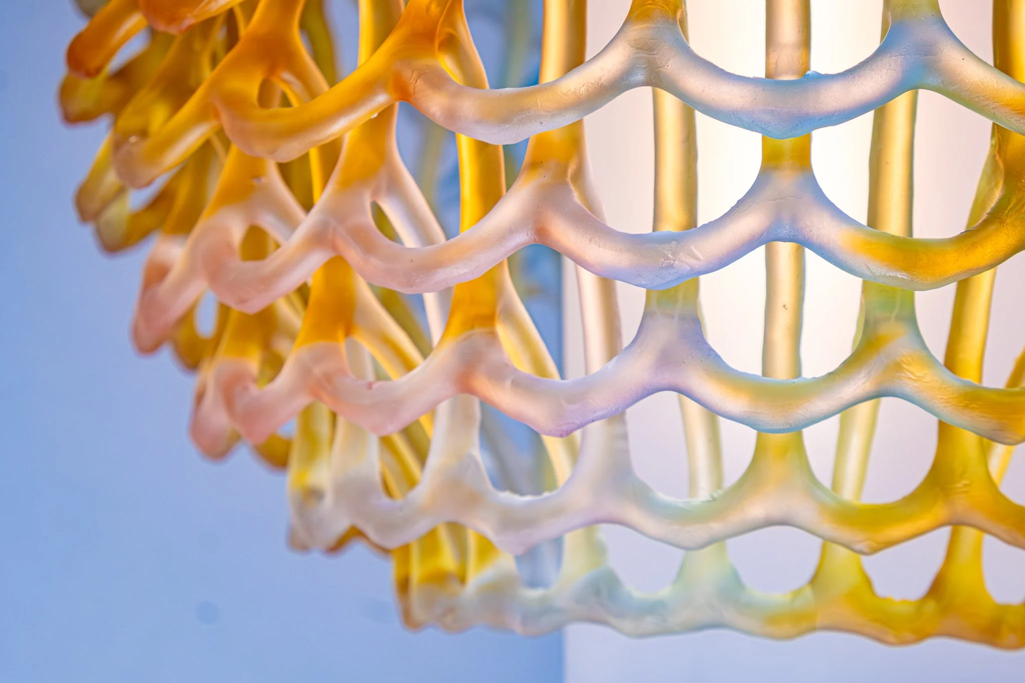 Close-up of a colorful, textured sculpture made of interconnected, wavy loops in pastel shades of white, pink, yellow, and blue.