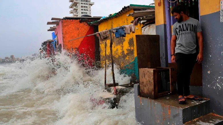 An Indian man stands near his house as waves caused by high tide hits the huts on the shore of the Arabian Sea in Mumbai, India, on July 3, 2019.
