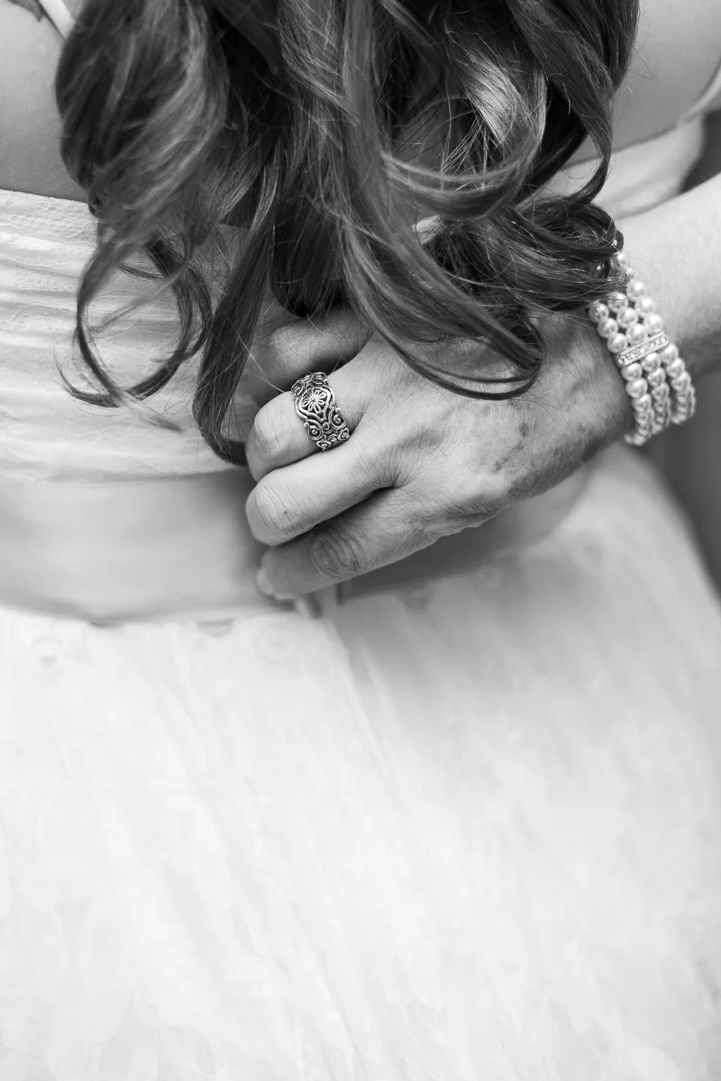 Mother of the bride zipping bride's dress before wedding ceremony. 