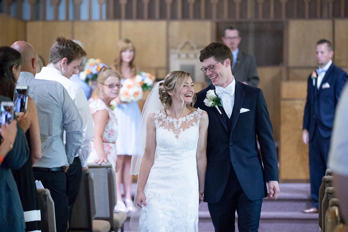 Bride and bridesmaid walking up the aisle smiling. 