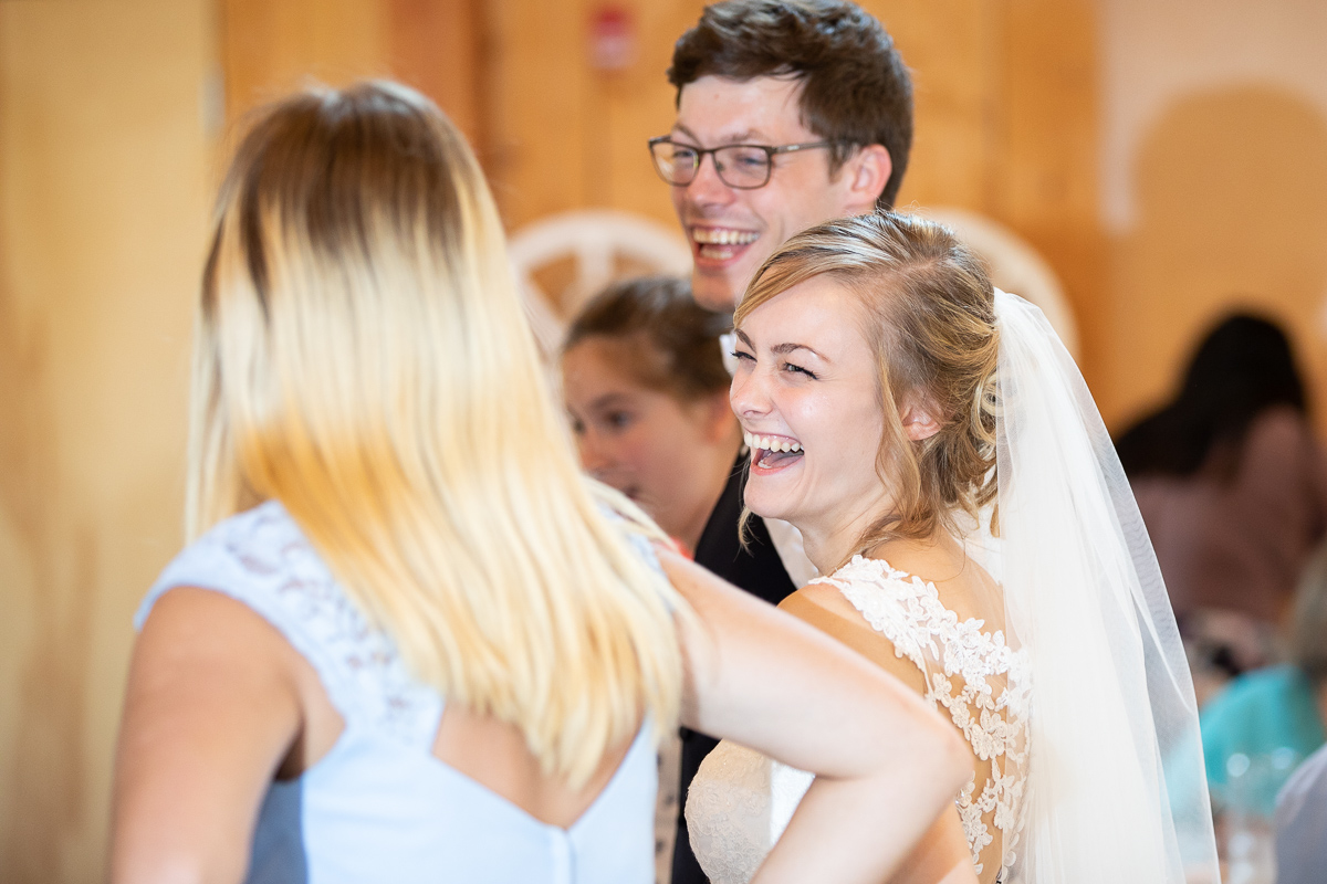 Bride laughing and dancing at wedding reception. 