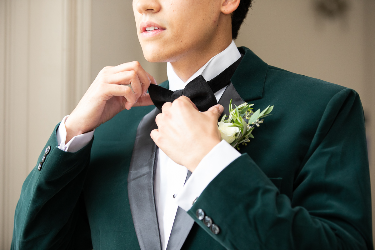 Groom putting on tie for wedding.