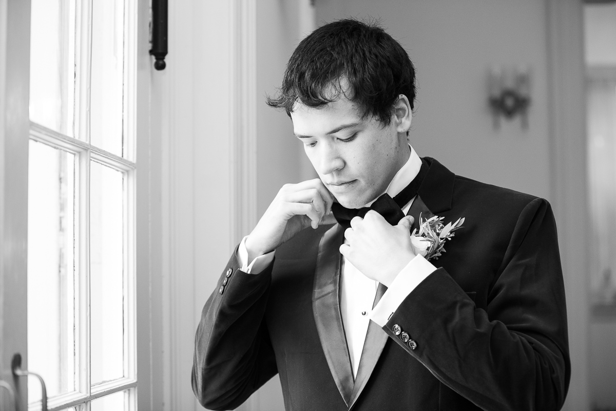 Groom putting on tie for wedding.