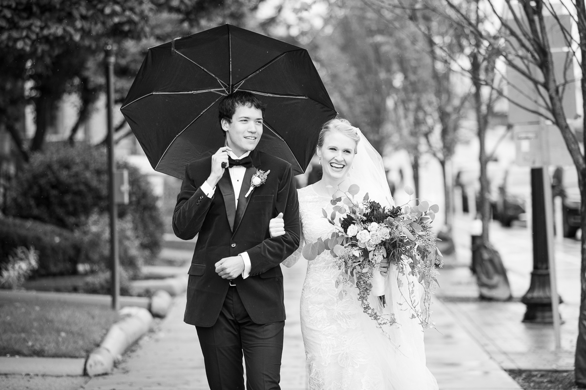 Bride and groom walking in downtown Boston in the rain.