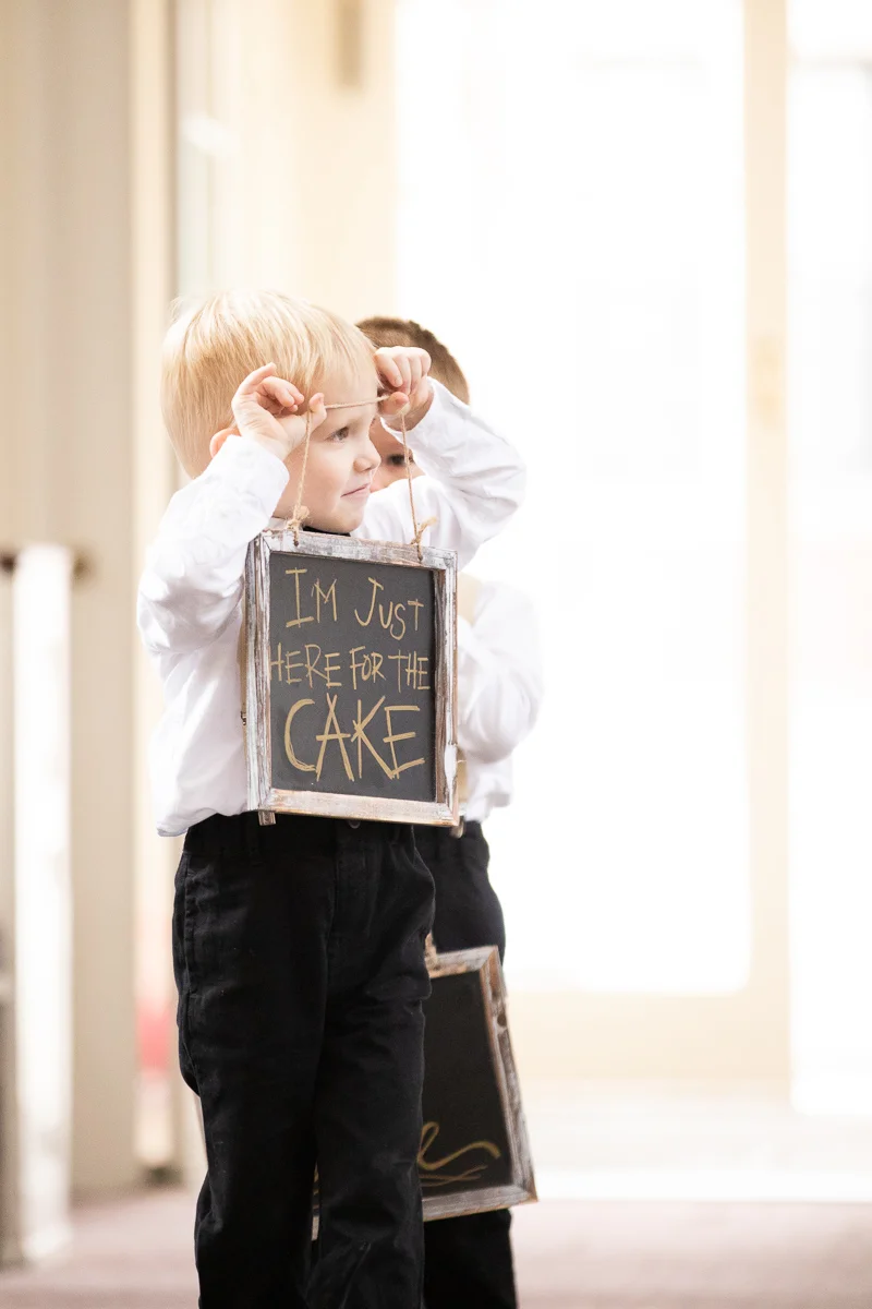 Ring bearer carrying sign down the aisle.