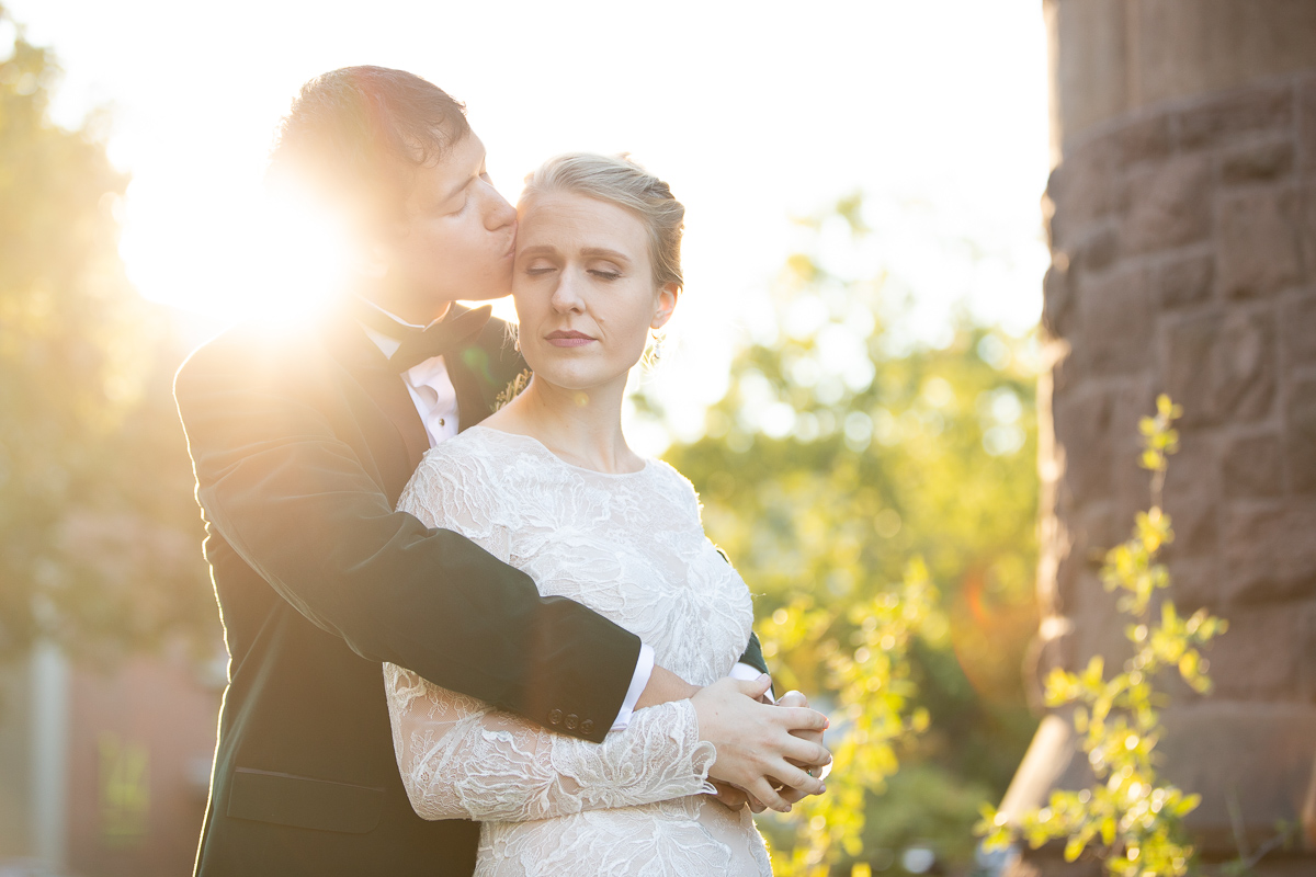 Groom giving bride a kiss at golden hour.